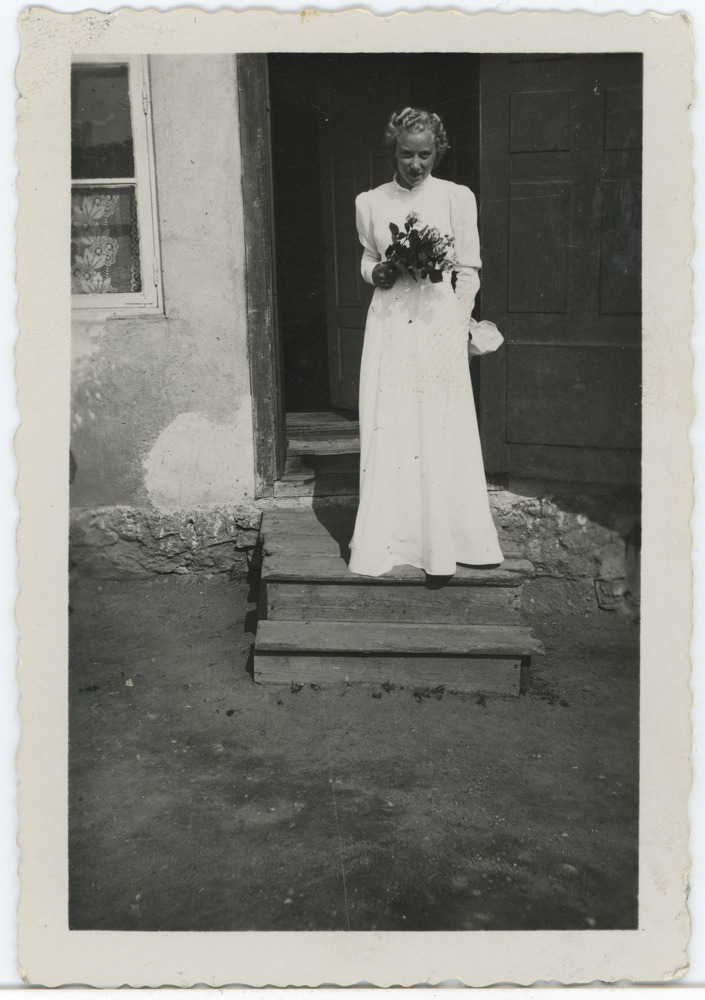 Laine Järv maja trepil seismas, lilled käes