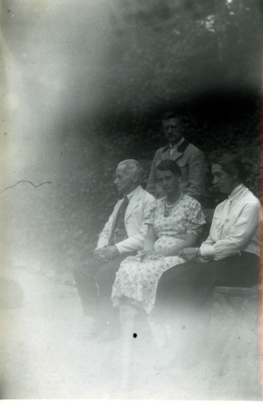 Seltskond aias. Istuvad kaks naist (Lore von Krusenstiern?) ning üks vanem mees, taga seisab prillidega mees.