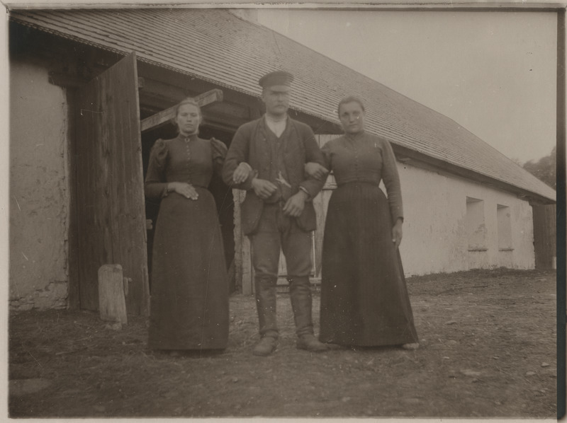 Mees kahe naisega mõisa hõrvalhoone taustal