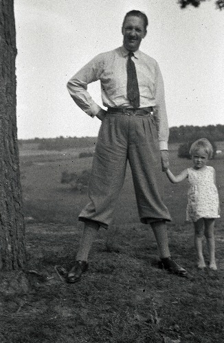 Suure männi kõrval seisab mees, väike tüdruk käekõrval.