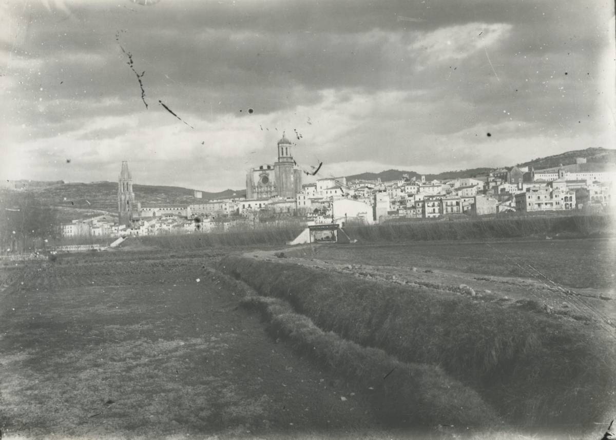 [Panoramic view from plan] - Panoramic view of the city of Girona from the plan. The route of the railway track is observed In the background the Cathedral of Girona and the church of Sant Feliu. On the right, behind the embankment of the train, the bastion of the Holy Cross.