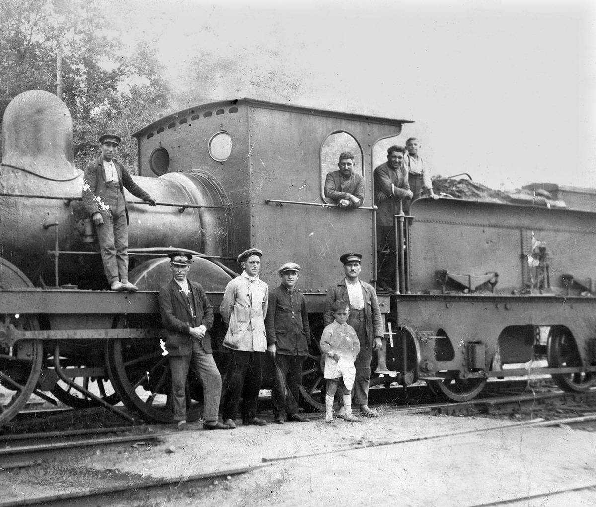 [Girona Station] - Portrait of different people around a locomotive stationed at the train station in Girona. It identifies Josep Feliu, a train driver.