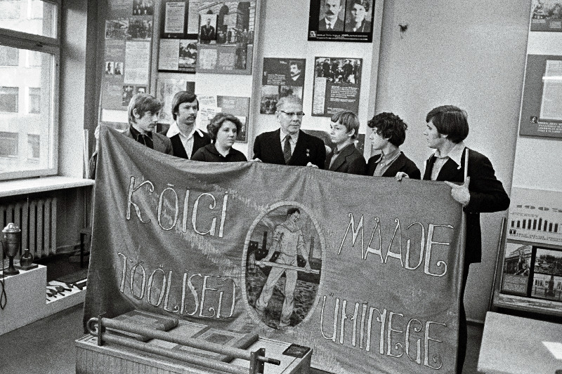 J. Lauristini nim. Tallinna Masinatehase tööveteran, sotsialistliku töö kangelane Alfred Valdov (keskel) näitab noortele töölistele 1917.a. võitluslippu.