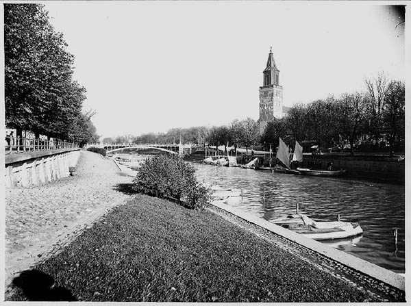 Vy från Åbo: Aura å med västra åstranden samt segelbåtar vid östra strandens kaj. Domkyrkobron med Åbo domkyrka i bakgrunden.