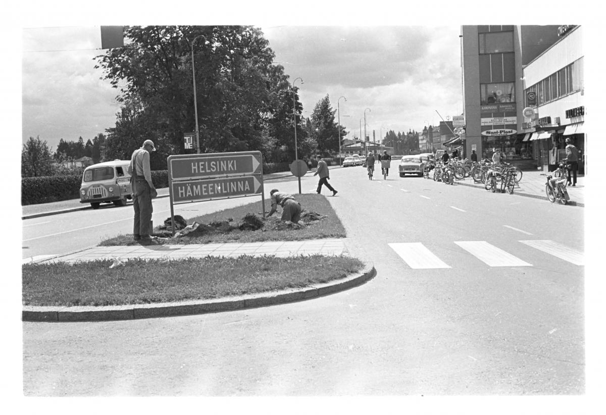 Työmiehiä kaivamassa liikenteenjakajassa, jossa on Helsinki, Hämeenlinna tienviitta Hämeenkadulla