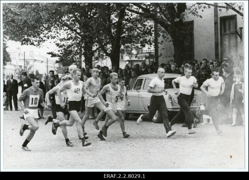 Rahvajooksul osalejad jooksevad Kuressaare tänaval. Eemal tänava äärel seisavad pealtvaatjaad