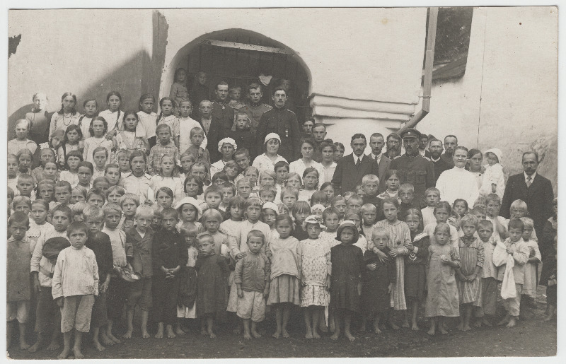 Ohvitserid [nende seas kolonel Siegfried Pinding] koos kohalike laste ning õpetajatega grupifotol hoone taustal