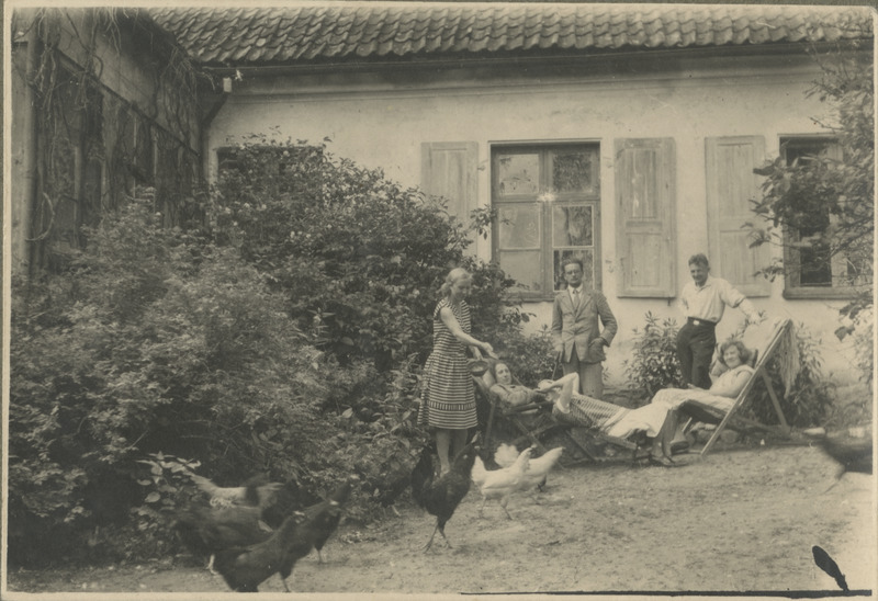 Eesti üliõpilaste seltsi "Veljesto" suvepäevad Võrumaal. Aiatoolides lesivad neiud ja püstiseisvad noormehed vaatamas kanu maja ees