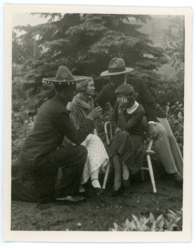Johannes ja Emilie Vares sõpradega õuel. Naised istuvad toolidel, seljaga fotol olev meesterahvas põlvitab, sombreero peas, Johannes Vares toetub abikaasa toolile