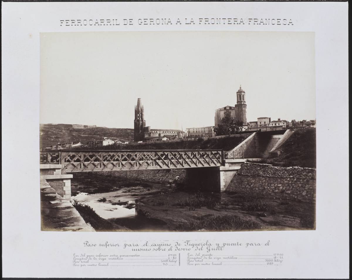 Railway from Gerona to the French Border. Lower pass for the Figuerola and flea road for the mismo on the Güell’s detour - The Clock Bridge over the river Güell. Secondly, the railroad embankment. In the background, from left to right, Montjuic mountain with the castle of the same name, the bell church of Sant Feliu and the Cathedral of Girona.