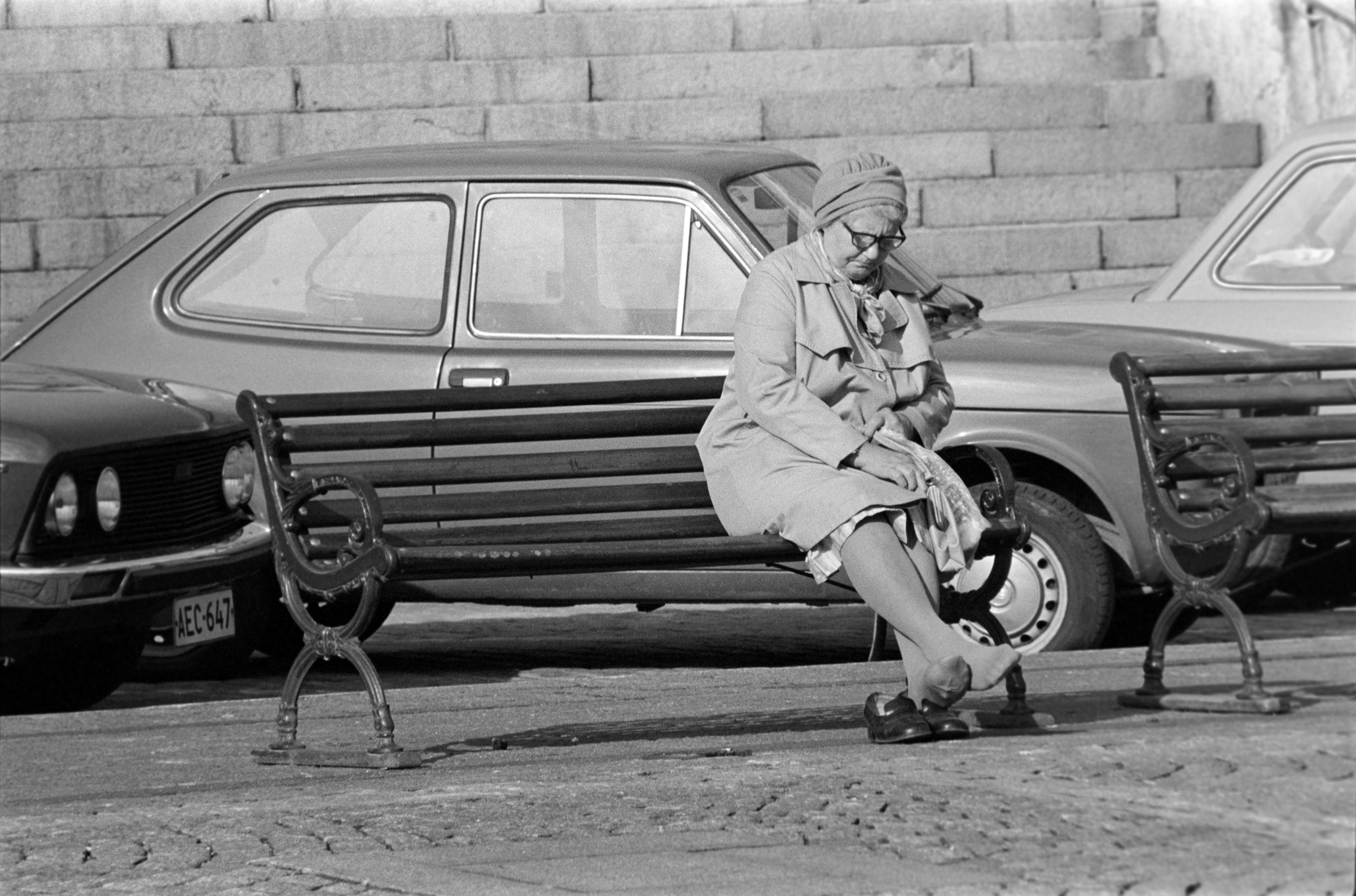 Nainen, joka on lepuuttaa jalkojaan penkillä Tuomiokirkon edessä.