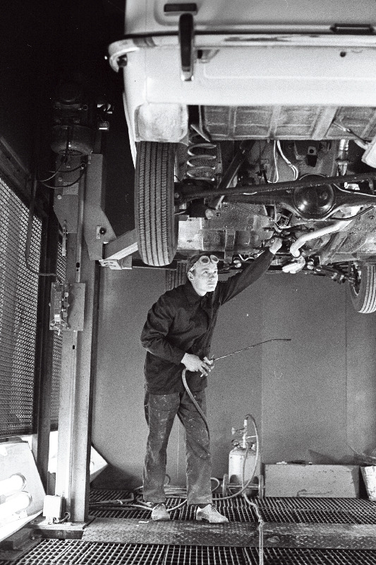 Volga Autotehase Tallinna Autokeskuse töötaja Ado Mälton auto põhja mastiksiga katmas.