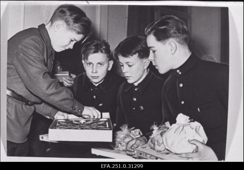 Endised Kaagvere lastekodu kasvandikud Kaagvere Tehnilise Kutsekooli nr. 1 õpilased Elmar Valk, Aadu Talpas, Vello Mitnits ja Heino Kaasik vaatamas kingituseks saadud esemeid.