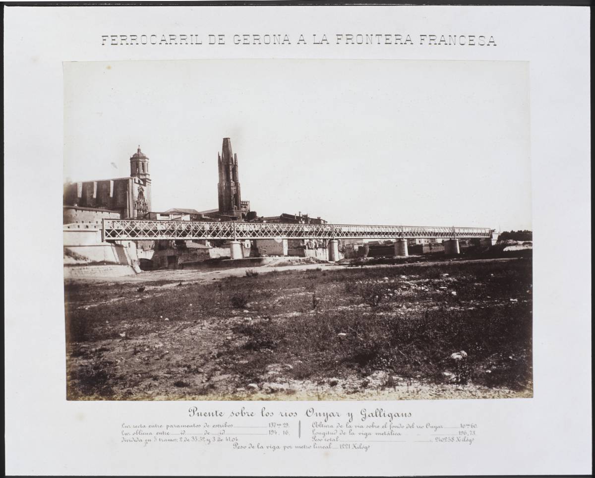 Railway from Gerona to the French Border. Bridge over the rivers Onyar and Galligants - Point of confluence between the rivers Ter and Onyar. In the central part, the railway bridge. In the background, the Cathedral of Girona and the bell church of Sant Feliu. On the right, the footbridge Portal de la Barca.