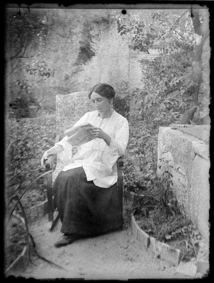 [Portrait of a woman] - Woman reading, sitting in a garden.