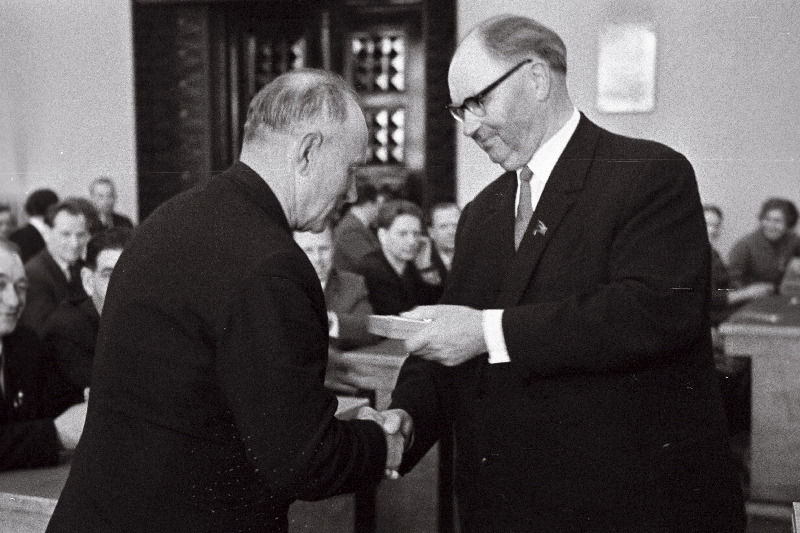 Eesti NSV Ülemnõukogu Presiidiumi esimees A. Müürisepp endisele partisanile E. Aasale juubelimedalit „20 aastat võidust 1941.-1945. a Suurest Isamaasõjas“ endiste partisanide  vabariiklikul kokkutulekul üle andmas.