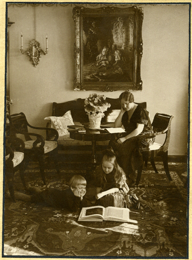 Hilda Tõnisson laua taga lugemas, Lembit Rein ja Hilja Tõnisson vaibal raamatut uurimas