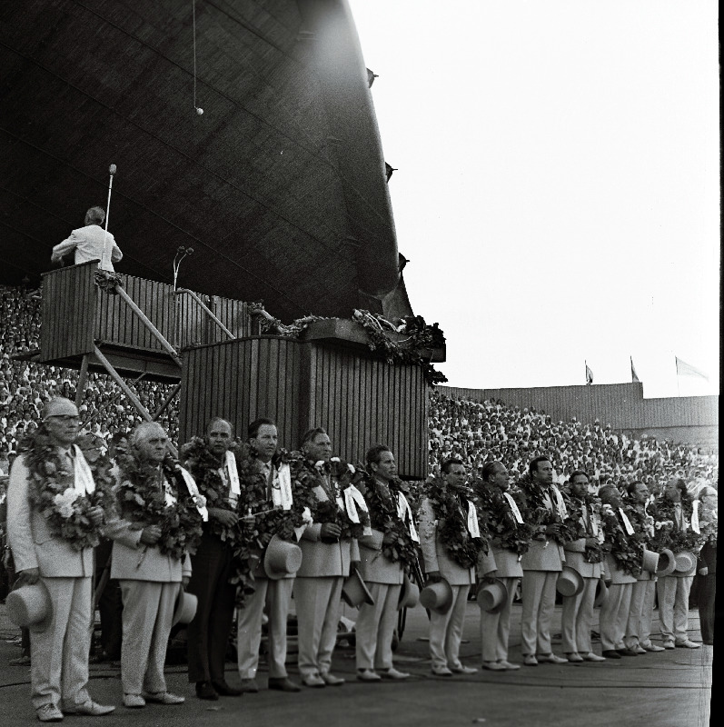 Juubelilaulupeo üldjuhid (vasakult): 1. Richard Ritsing, 2. Leopold Vigla, 3. üldlaulupeo peakomisjoni esimees Arnold Green, 4. Heino Kaljuste, 5. Lembit Verlin, 6. Arvo Ratassepp, 7. Uno Järvelo, 8. Helmut Orusaar,9. Neeme Järvi, 10. John Tungal (?), 12. Heino Rannap, 13. Aksel Pajupuu. Dirigendipuldis Jüri Variste.