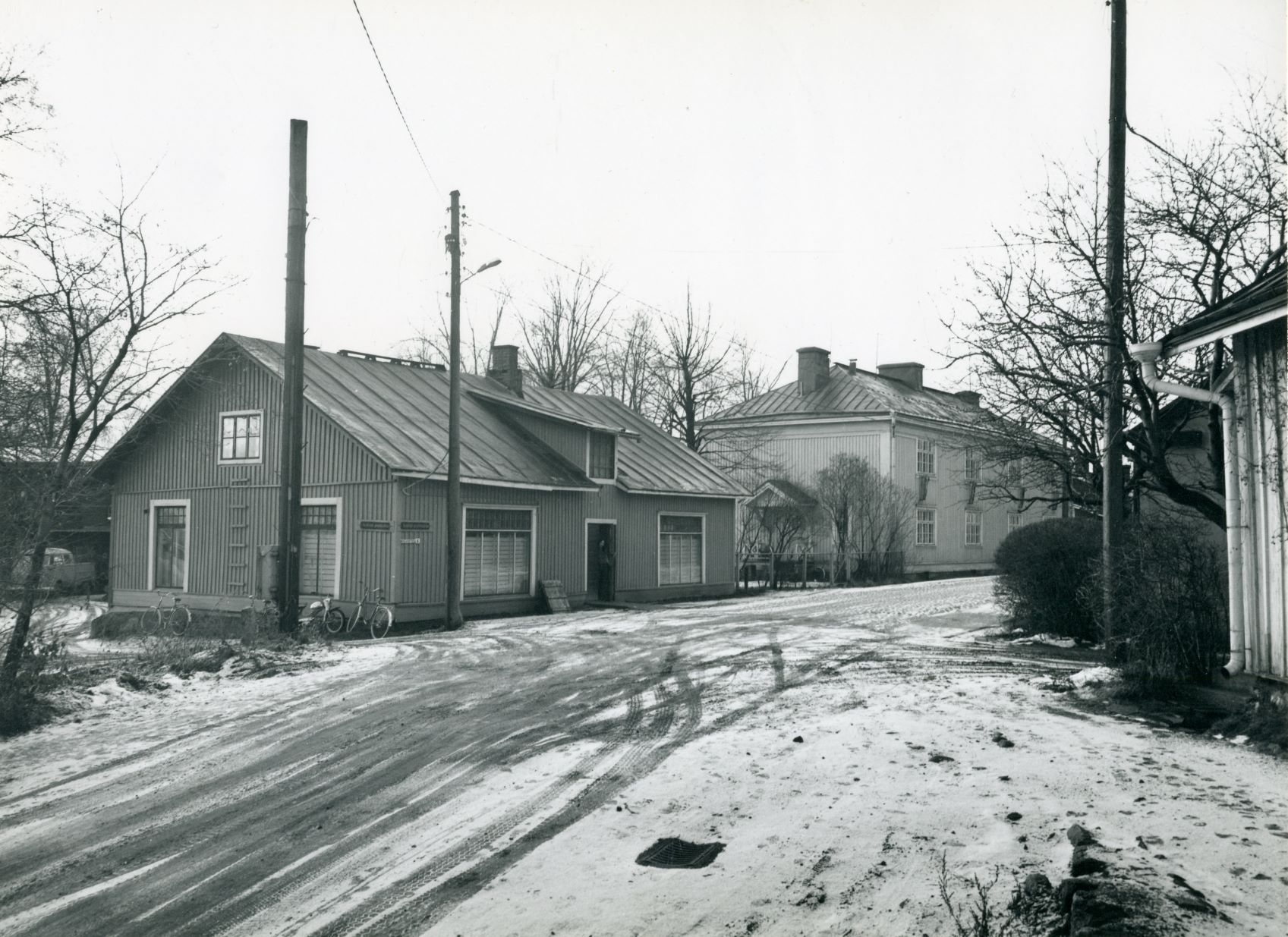Maantien ja Nyberginpolun risteys, edempänä kuvassa oleva talo on purettu 1970-luvulla. Seuraava rakennus tiellä on VR:n kaksikerroksinen kasarmi. Kuva: Riihimäen kaupunginmuseo
