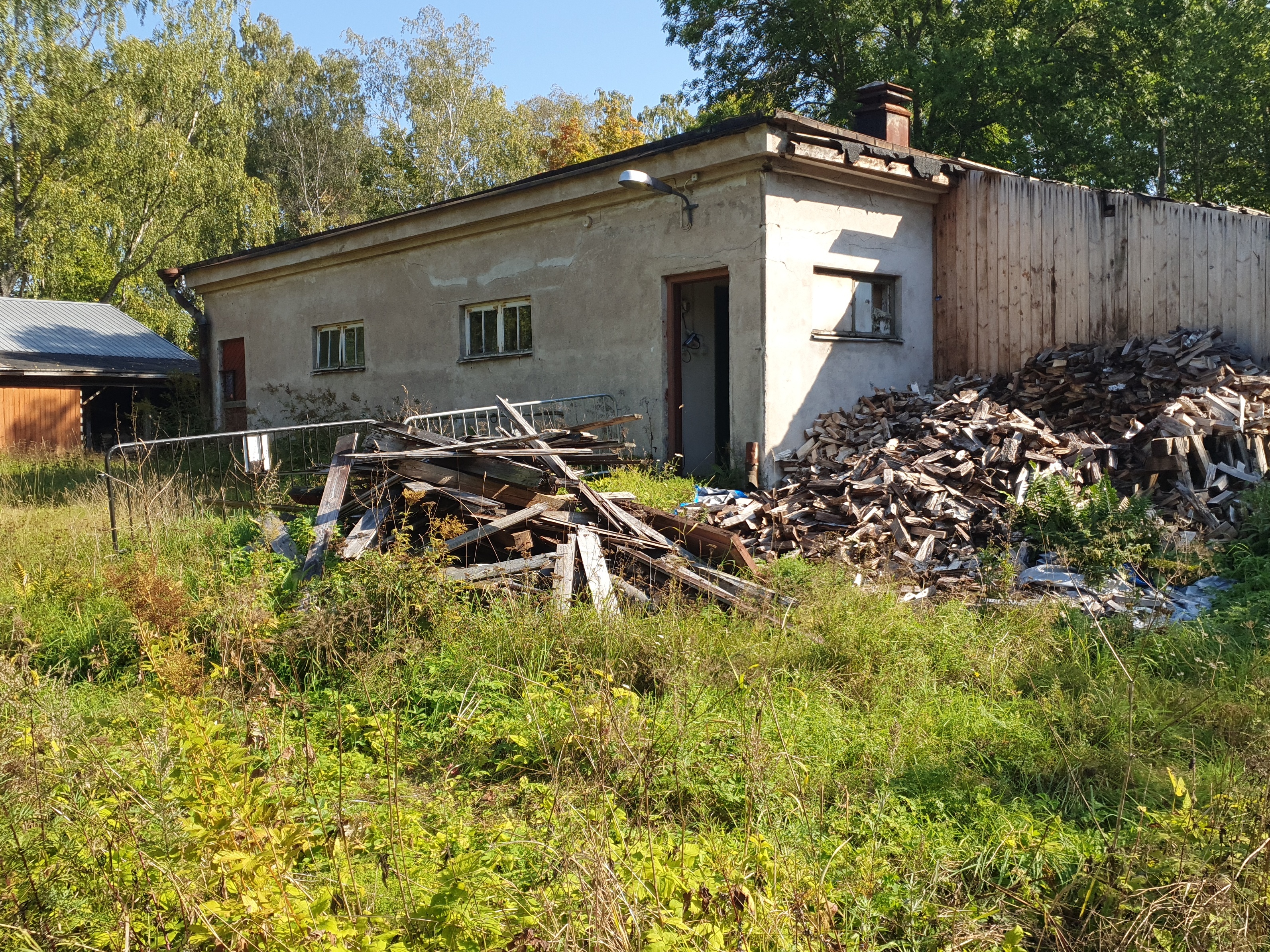 Paloaseman palokalustovaja Vallisaaressa. Siinä säilytettiin aikanaan T-mallista Fordia, kuorma-autoa ja hevosvetoisia kärryjä. Keskimmäisestä ovesta kuljettiin kahden hevosen talliin ja viereisestä punaisesta ovesta hevosten rehu- ja heinävarastoon. Pihapiiriin kuuluu myös vasemmassa reunassa näkyvä puusepänverstas. Valokuva on otettu aurinkoisella säällä. rephoto
