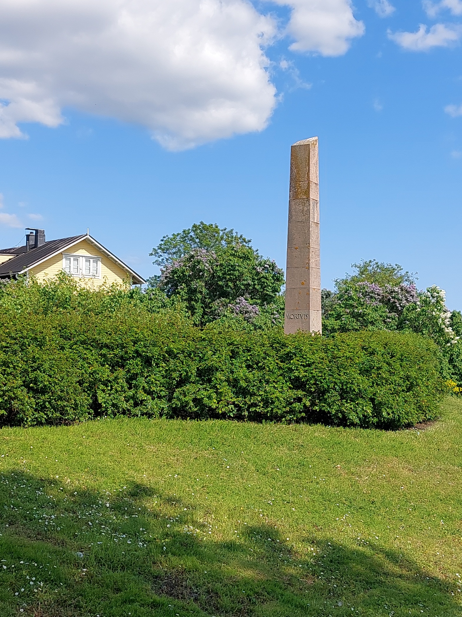 Suomenlinna, Susisaari. Mies valokuvaa Linnoituksessa menehtyneiden muistomerkkiä. Arkkitehti Elsi Borgin suunnittelema obeliskimainen muistokivi Mortuis (kuolleille, menehtyneille) on pystytetty 1951 Suomenlinnassa eri katastrofeissa menehtyneiden muistoksi. Muistomerkkiin on kaiverrettu vuosiluvut 1808, 1855, 1906, 1917, 1918, 1937 ja se on sijoitettu Vallisaaren räjähdysonnettomuuden uhrien hautapaikalle Piiperin puiston itäpuolelle. rephoto
