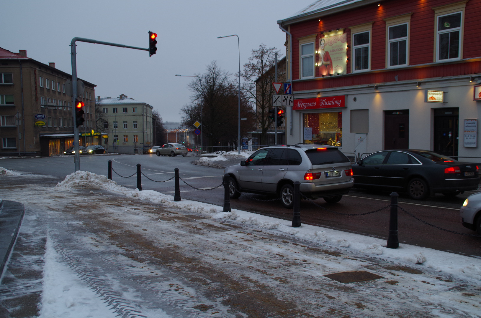 Postijaama plats Riia mäel.
Esiplaanil puuputkad ja hobuvankrid mitmesuguse kraamiga. Paremal pool (Pihkva t; hilisem Võru mnt) asetsevatel majadel eesti- ja venekeelsed sildid: Vürtsi kauplus; Õlle pood
Vaade postijaama poolt kesklinna suunas.  Tartu, 20. saj. algus. rephoto