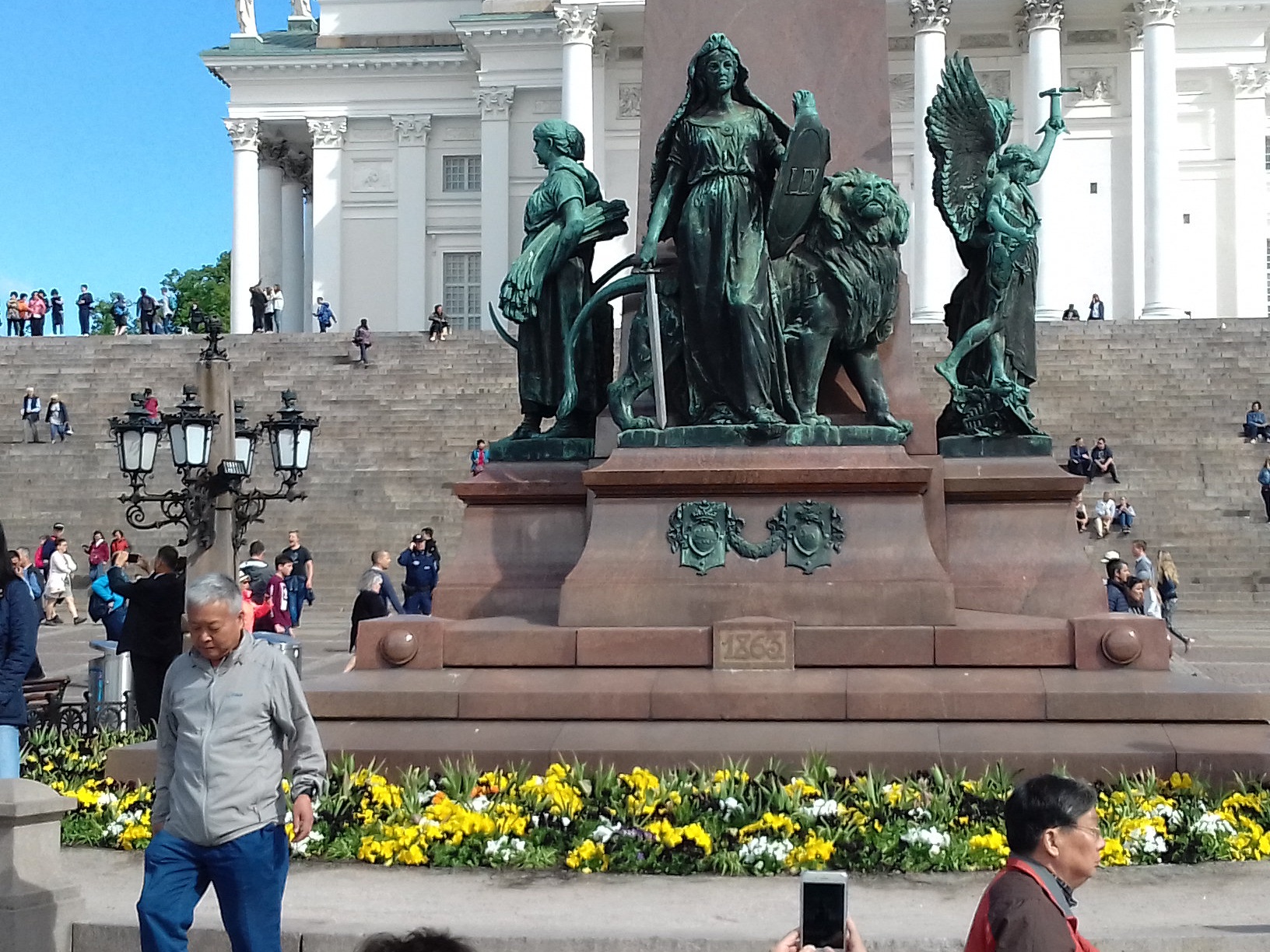 Kommunistien vappujuhla Senaatintorilla. Ihmisiä istumassa Aleksanteri II:n patsaan juurella. rephoto