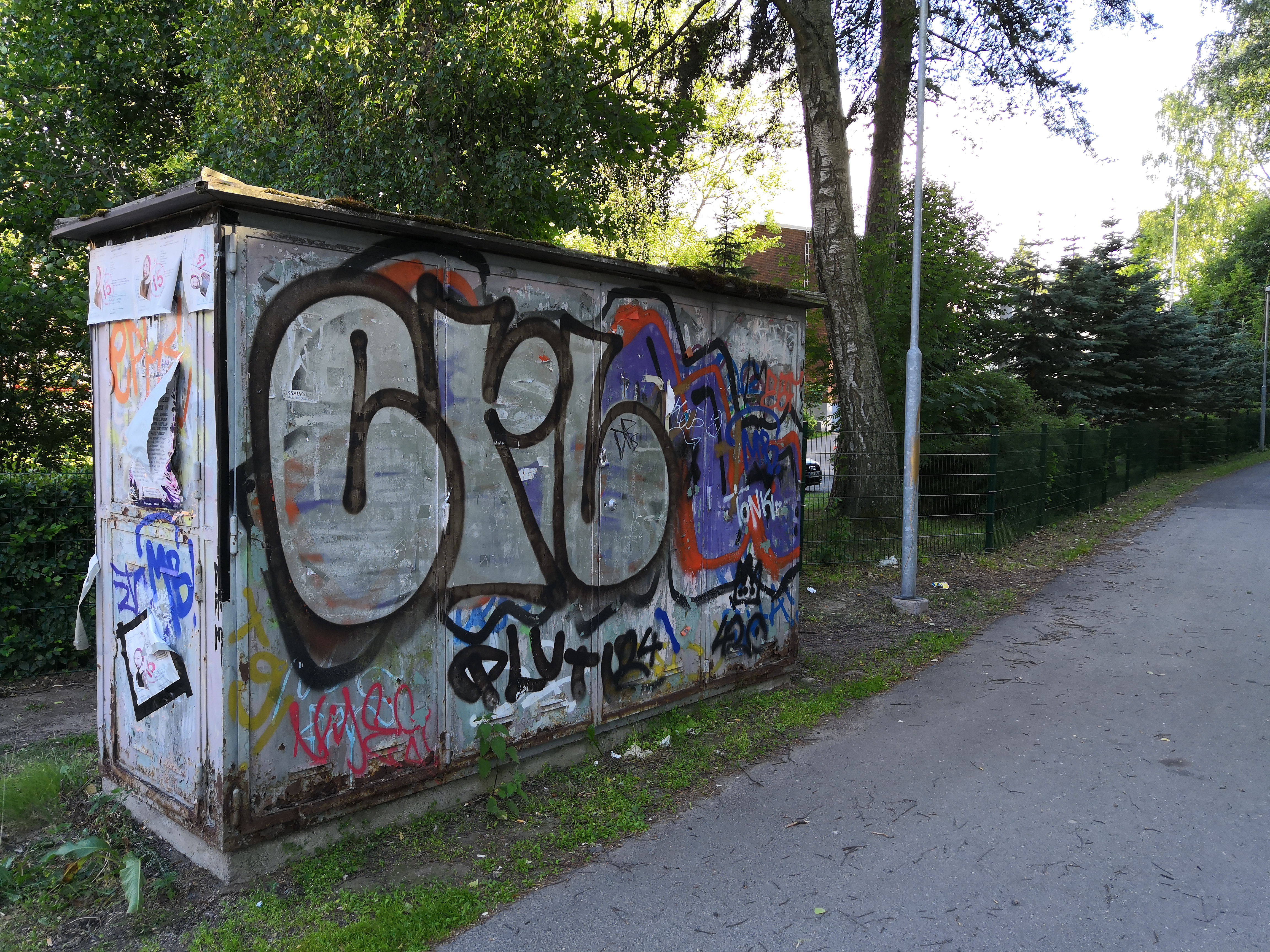 Graffitien ja mainosjulisteiden värikkäästi peittämä sähkökaappi rephoto