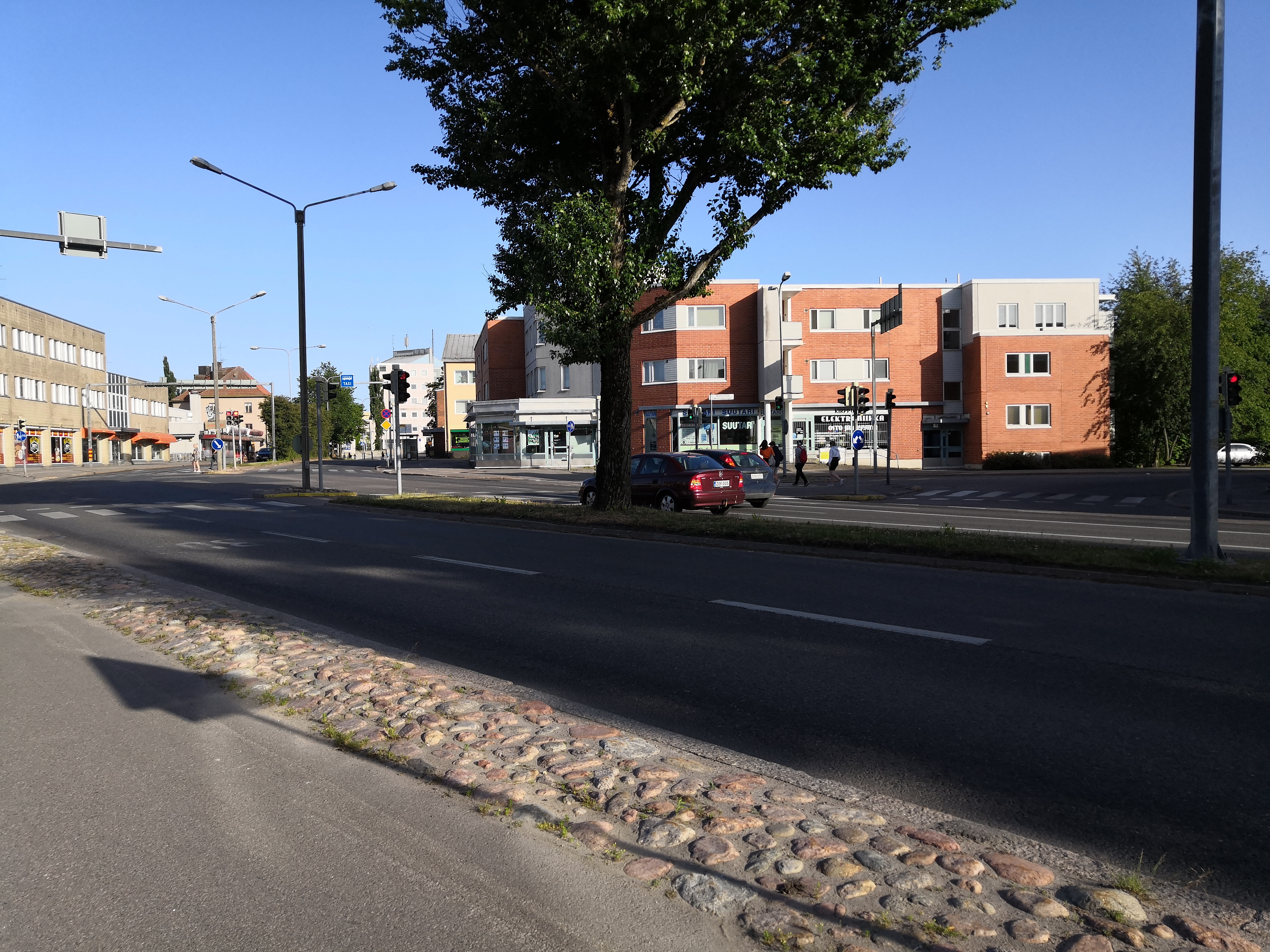 Kirkonkyläntie Ylä-Malmilla. Oikealla numerot 12, 10 sekä 8 ja vasemmalla valkoisen auton ja liikennevalojen jälkeen numerot 5 ja 3. Risteyksestäm oikealle alkaa Markkinatie. rephoto