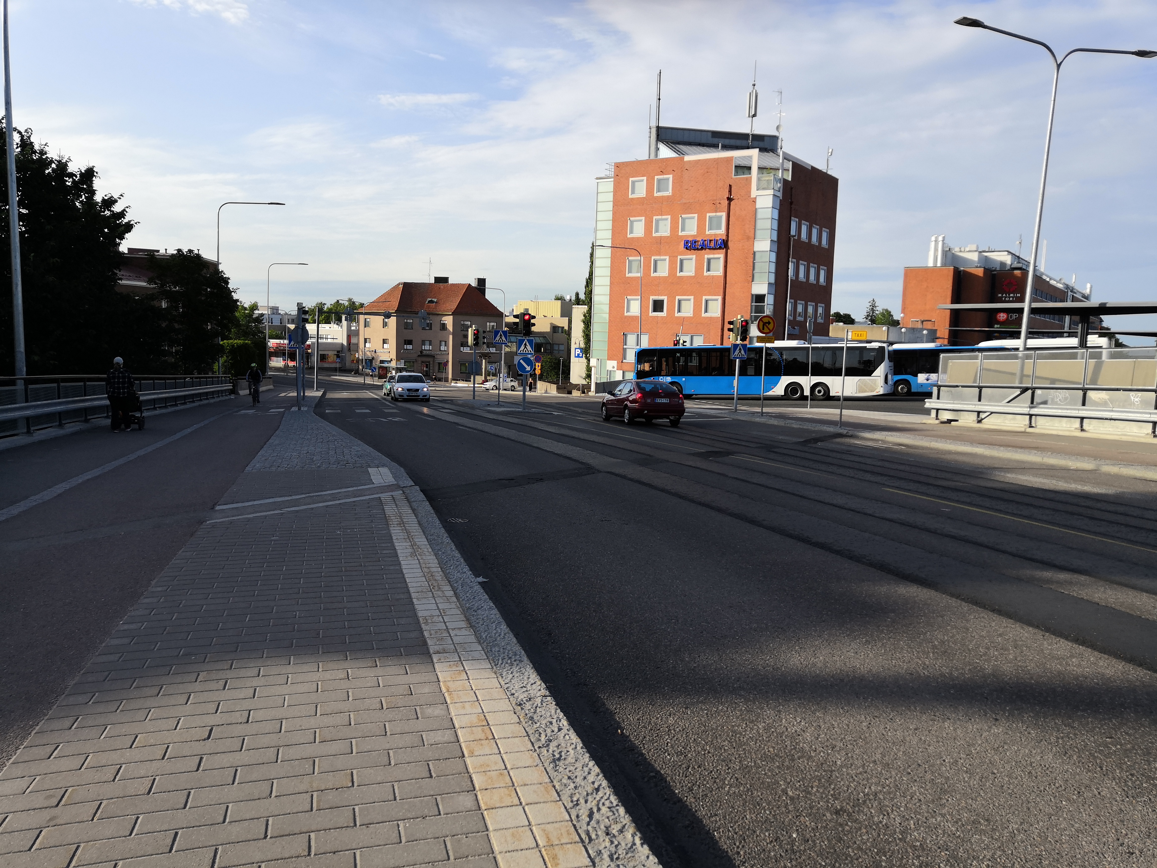 Malmi, Ylä-Malmi, Kirkonkyläntie. Näkymä pääradan ylittävältä maantiesillalta Kirkonkyläntien alkupäästä pohjoiseen, Ylä-Malmin suuntaan. Vasemmalla Malmin Elannon rakennuksessa  E-Alennushalli. Oikealla Suomen Maanviljelijäin Kauppa SMK:n myyntikonttori ja varasto paikalla, jossa nykyisin on Malmin kauppakeskus ja Ylä-Malmin tori. rephoto