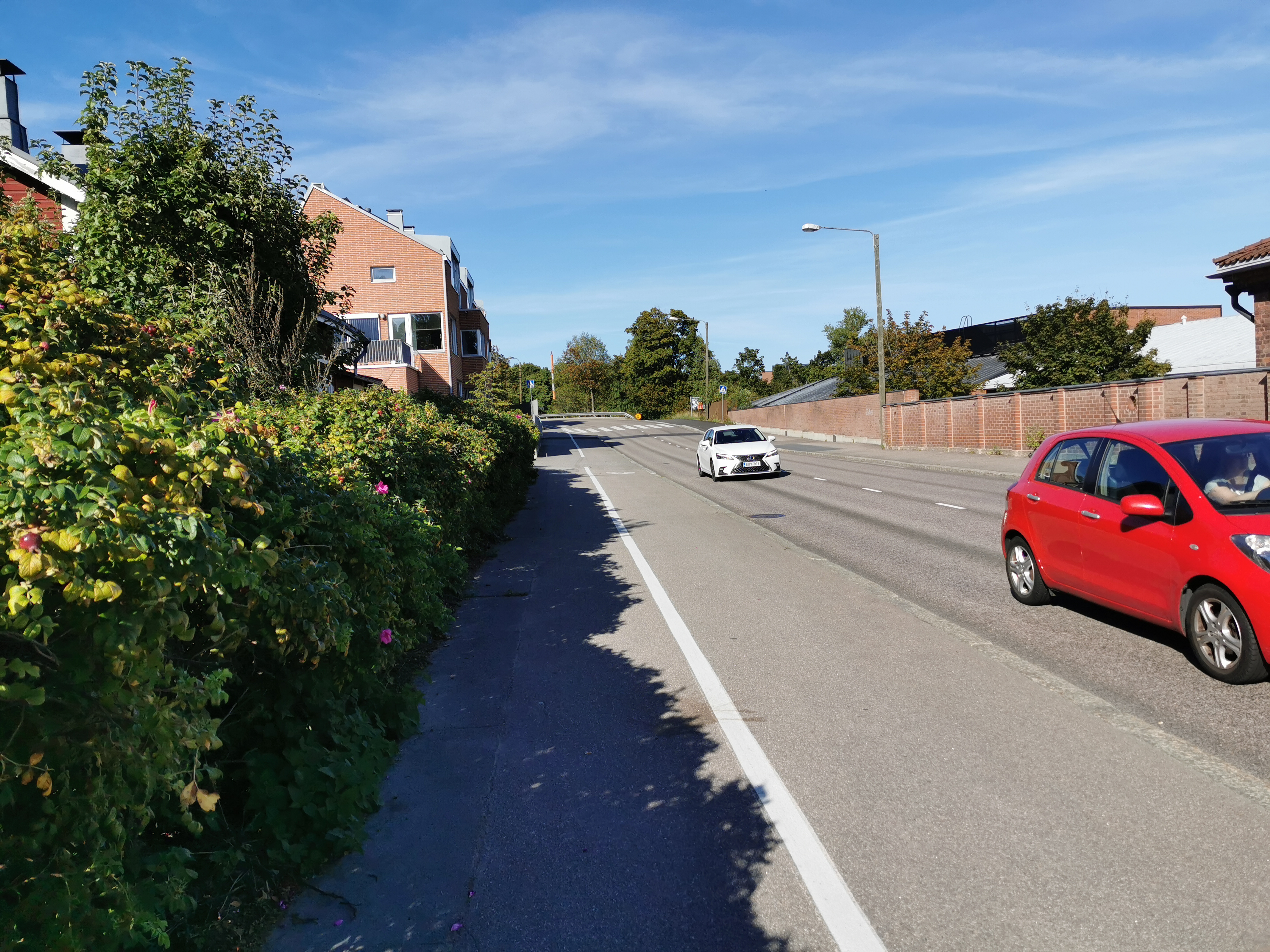 Itäistä Viertotietä (nykyisin Hämeentie) Vanhan kaupungin (nyk. Vanhakaupunki) eteläosien kohdilla. Oikealla takana nykyisen Koskipuiston alue. Helsingin Muinaismuistolautakunta  ja valokuvaaja Signe Brander "sunnuntairetkellä" katsastamassa kuvauskohteita Vanhassakaupungissa Itäisellä Viertotiellä (Hämeentie 166, 165). rephoto