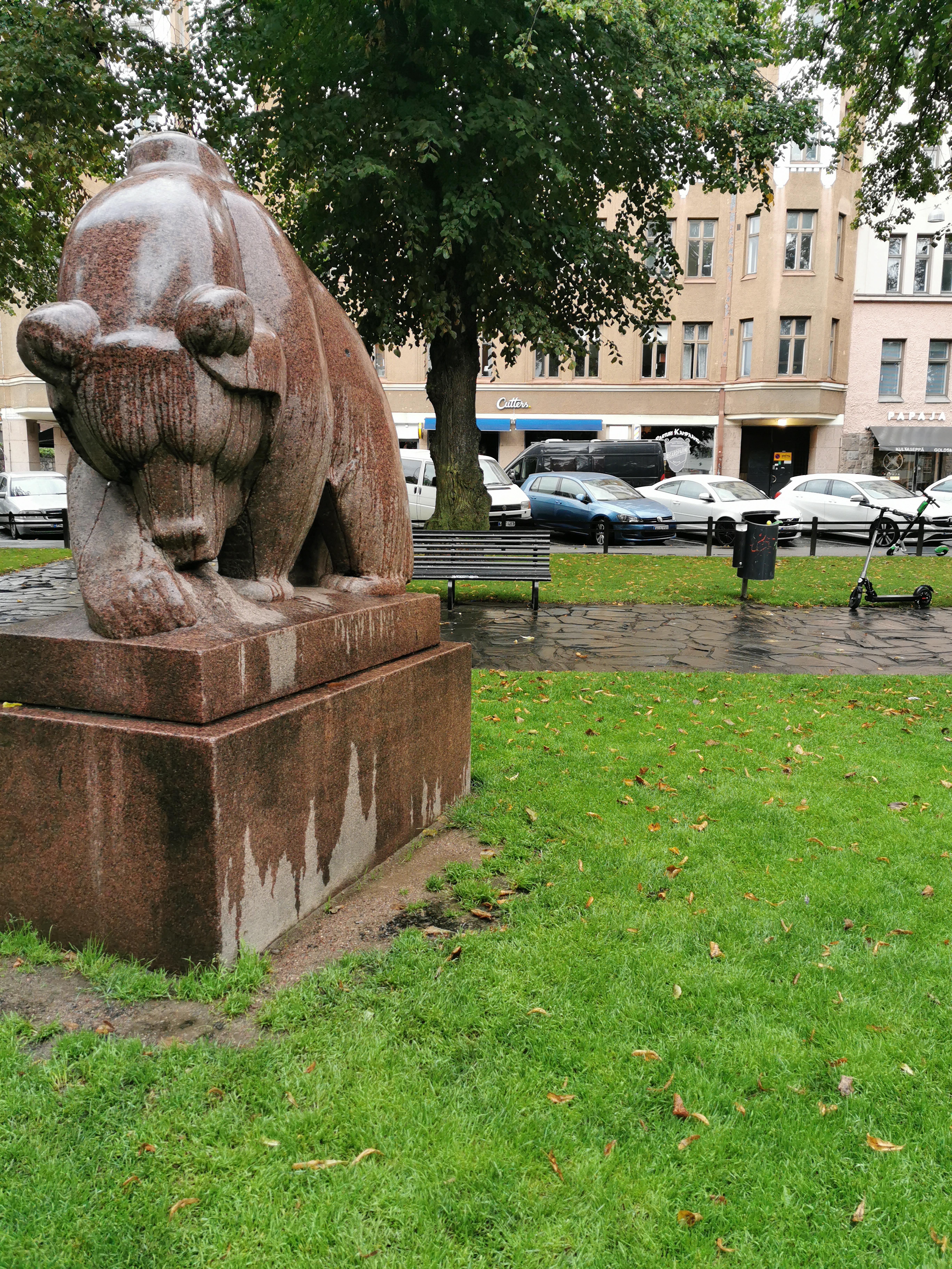 Nainen ja sotilasunivormuinen mies Karhupuistossa, vasemmalla kuvanveistäjä Jussi Mäntysen veistos Mesikämmen muurahaispesällä. Taustalla kerrostalo Agricolankatu 13. rephoto