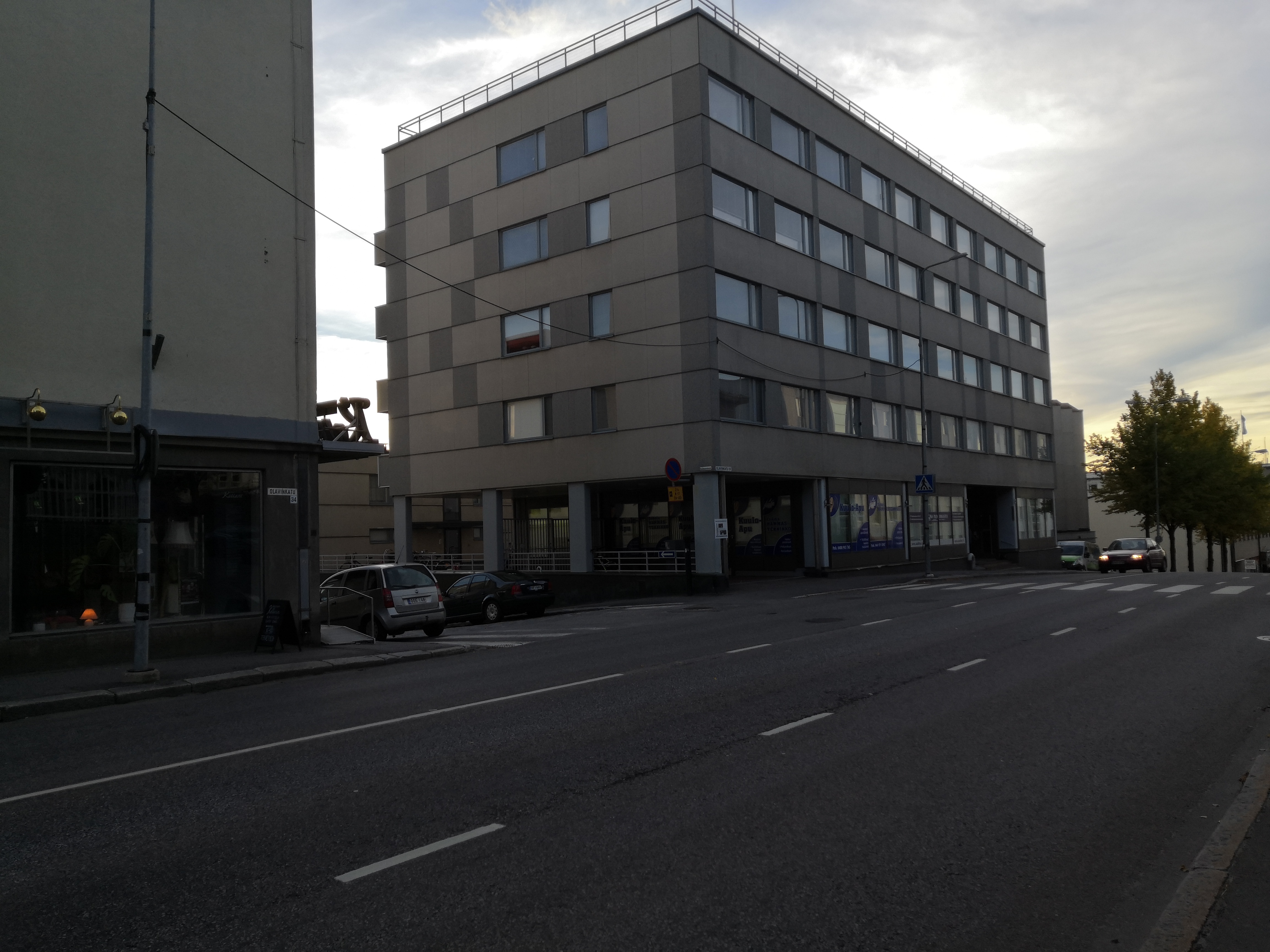 Entinen raatihuone, myöhemmin posti (Olavinkatu 36) idästä Olavinkadun yli. Olavinkatu 34:n kohdalla puuaidassa mainoskaappeja, katu mukulakivipäällysteinen, kangaskattoinen auto, jalankulkijoita. Takana oikealla And. Auvisen rakennus (Olavinkatu 38). rephoto