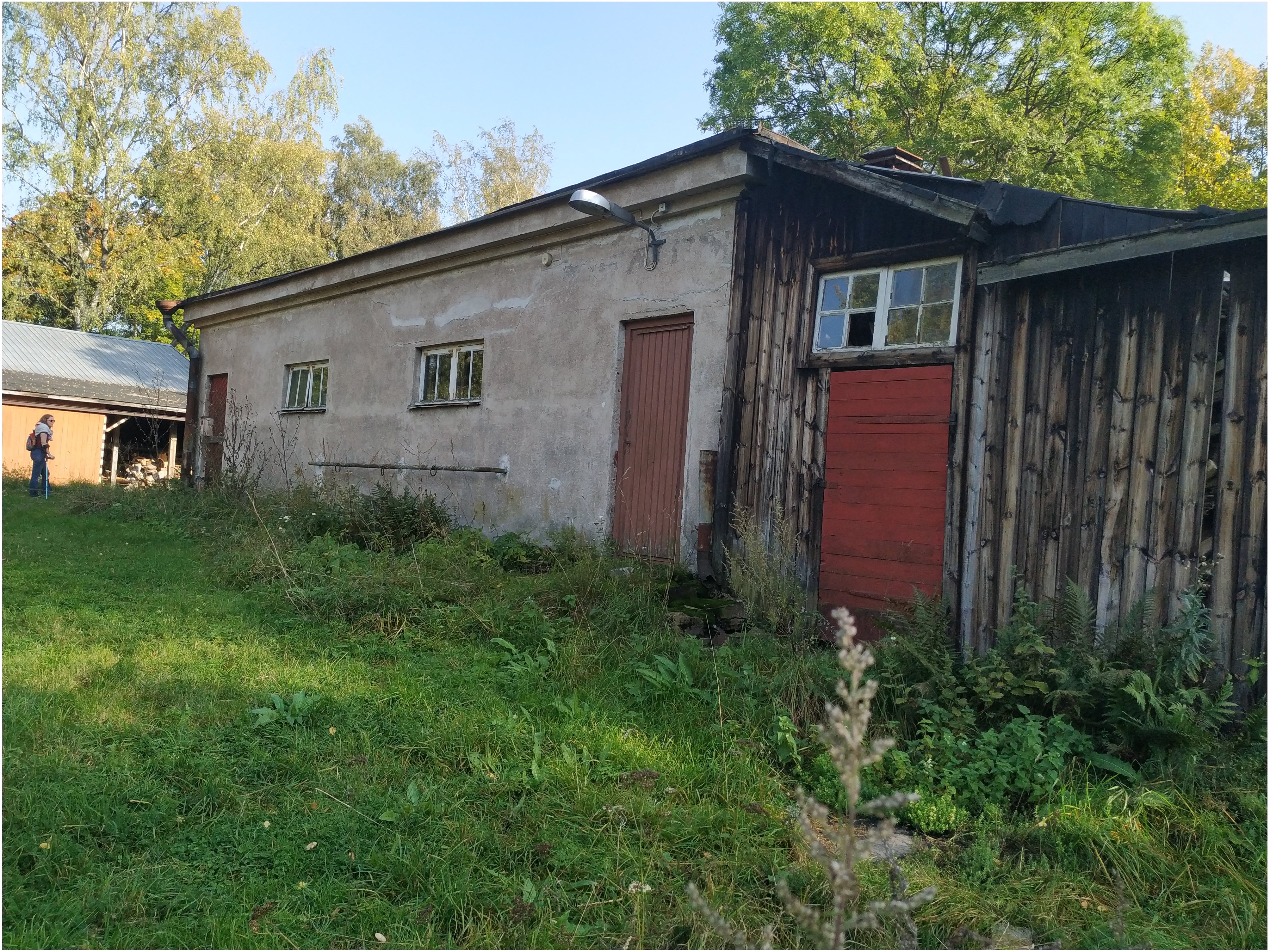 Paloaseman palokalustovaja Vallisaaressa. Siinä säilytettiin aikanaan T-mallista Fordia, kuorma-autoa ja hevosvetoisia kärryjä. Keskimmäisestä ovesta kuljettiin kahden hevosen talliin ja viereisestä punaisesta ovesta hevosten rehu- ja heinävarastoon. Pihapiiriin kuuluu myös vasemmassa reunassa näkyvä puusepänverstas. Valokuva on otettu aurinkoisella säällä. rephoto