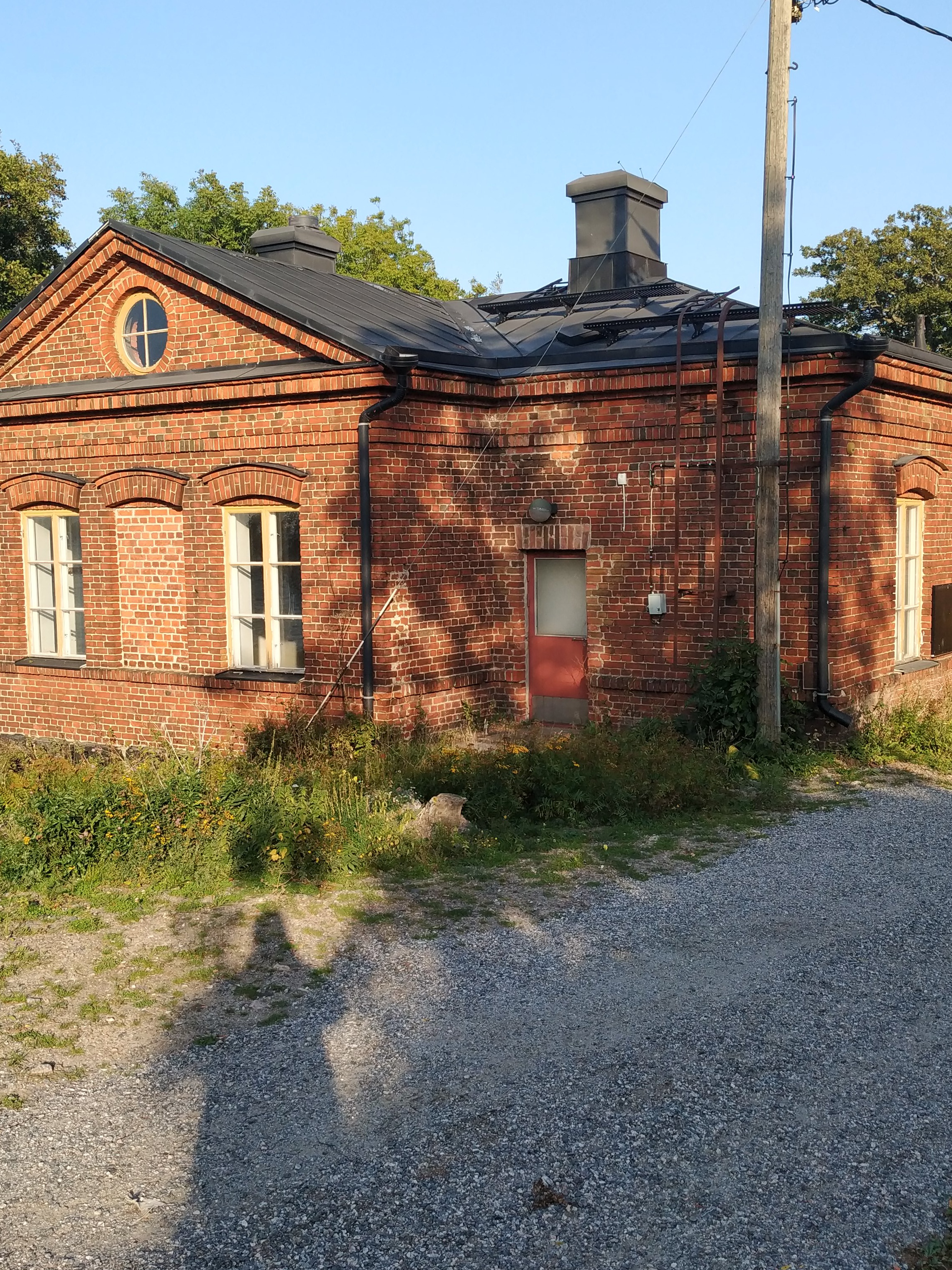 Vallisaarelaisia saaren luotsitalon pihapiirissä. Kaksi miehistä on sotilasunivormussa. Toisella naisista on sylissään pieni lapsi. Taustalla näkyvä tiilirakennus on luotsitalon sauna- ja pyykkitupa. rephoto