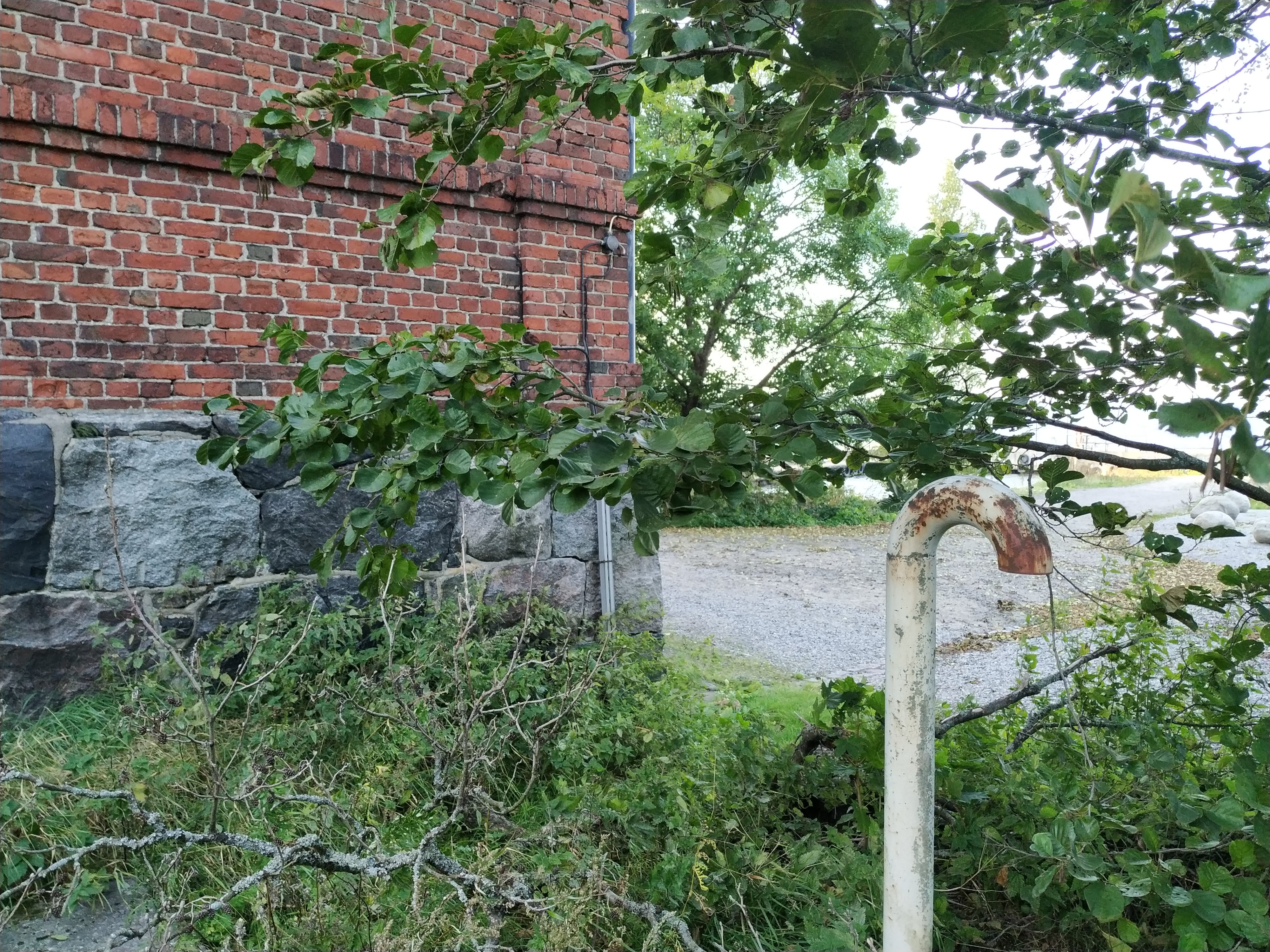Kolme lasta istuu Vallisaaren luotsitalon itäpäädyssä. Taustalla näkyy luotsitalon edustalla oleva venesatama ja äärimmäisenä oikealla armeijan yhteyslaiva Axel von Fersen. rephoto