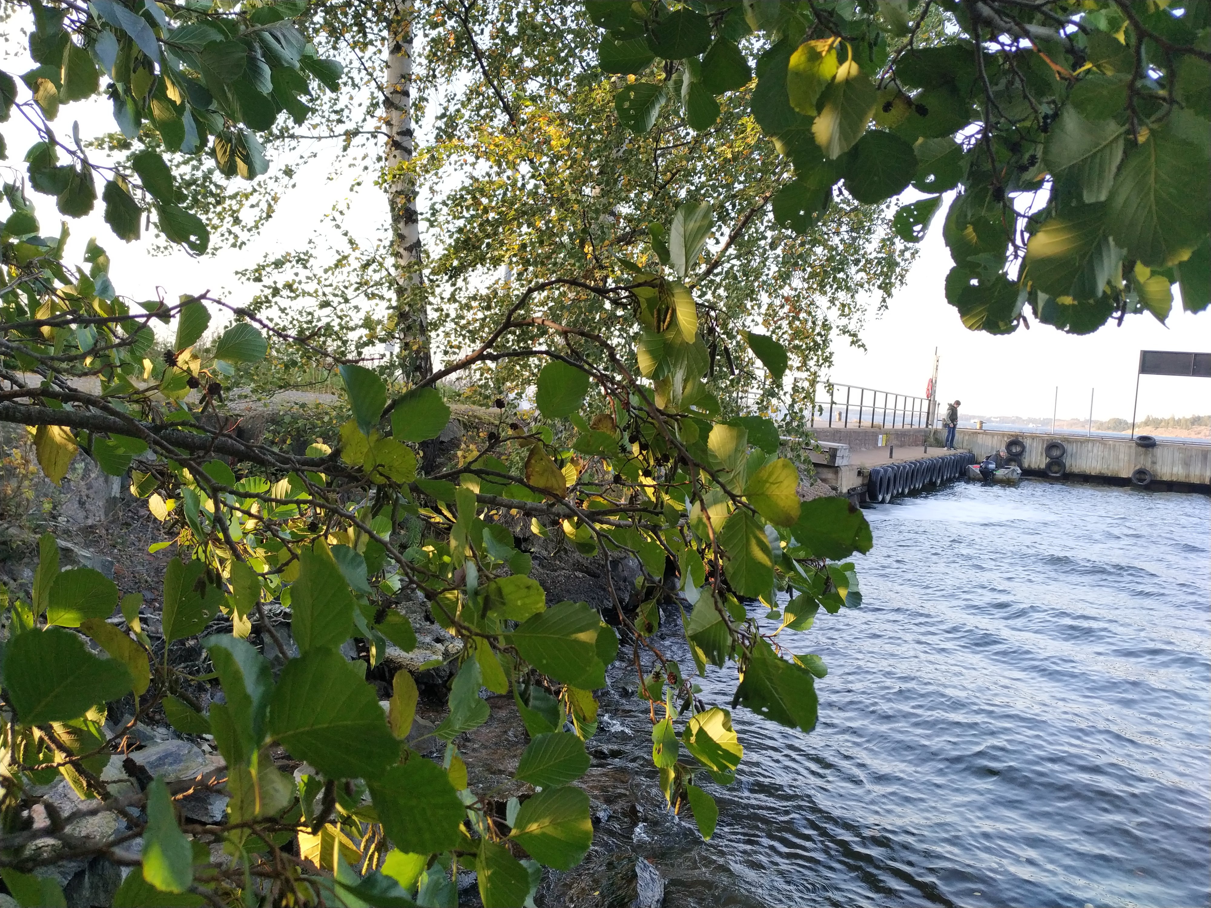 Väkeä Vallisaaren Päälaiturin luona. Ihmiset jonottavat pääsyä vartiolle näyttääkseen kulkulupansa saavuttuaan veneellä saareen. Vallisaari oli alunperin venäläisen varuskunnan käytössä ollut saari ja Suomen itsenäistymisen jälkeen Suomen armeijan käytössä, ja siten pääsy saarelle oli luvanvaraista. Valokuva on otettu saaren pohjoisrannasta. On kevät ja maassa on vielä jäämiä lumesta ja jäästä. rephoto