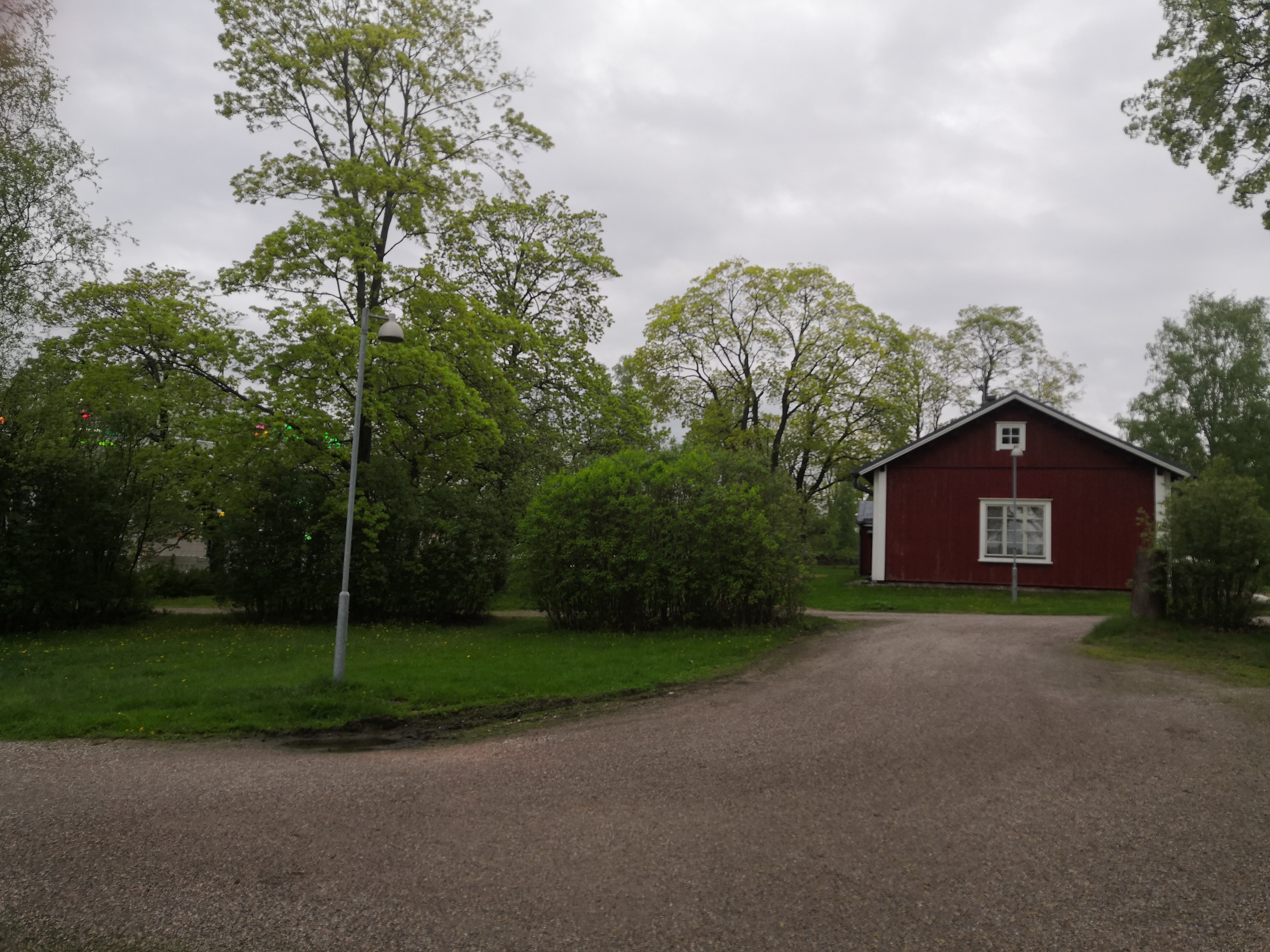 Latokartanonkaari 3. Näkymä Viikin Latokartanosta Viikintien suunnalta nykyisen Viikinkaaren suuntaan. Oikealla tien laidassa punainen puurakenteinen asuinrakennus Viikin koetilan työntekijöitä varten. Taustalla nostokurki Helsingin yliopiston Viikin maataloustieteellisten laitosten rakennustyömaalla nykyisellä Latokartanonkaarella. Taaempana Pihlajamäen kallioita. rephoto