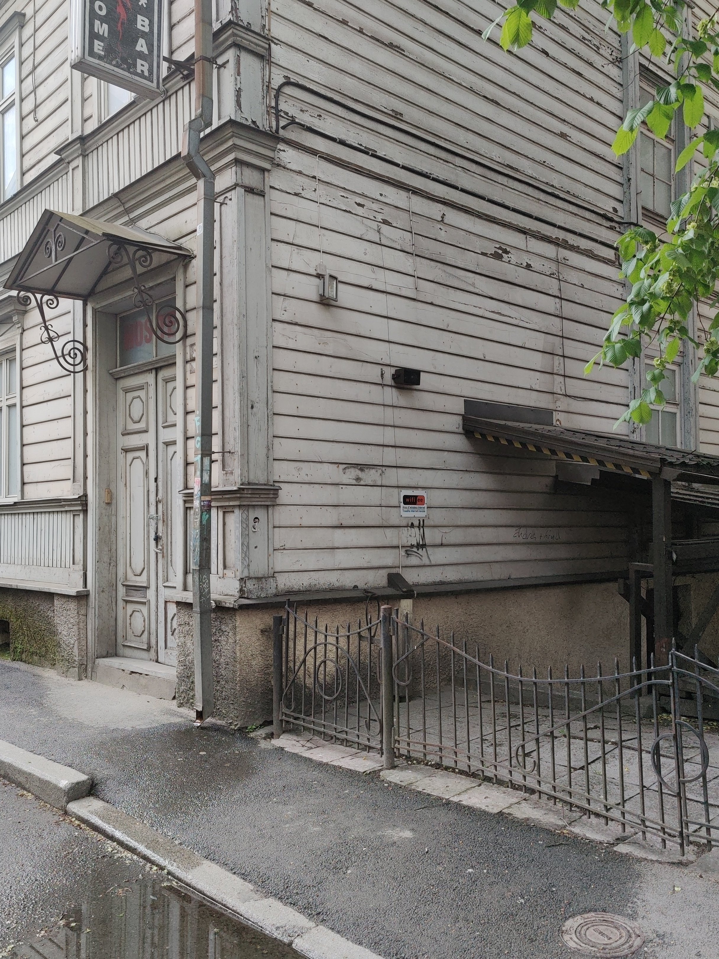 Wooden house on Sakala Street. Outdoor door and squeezing. A slogan on the wall: "Come home." rephoto
