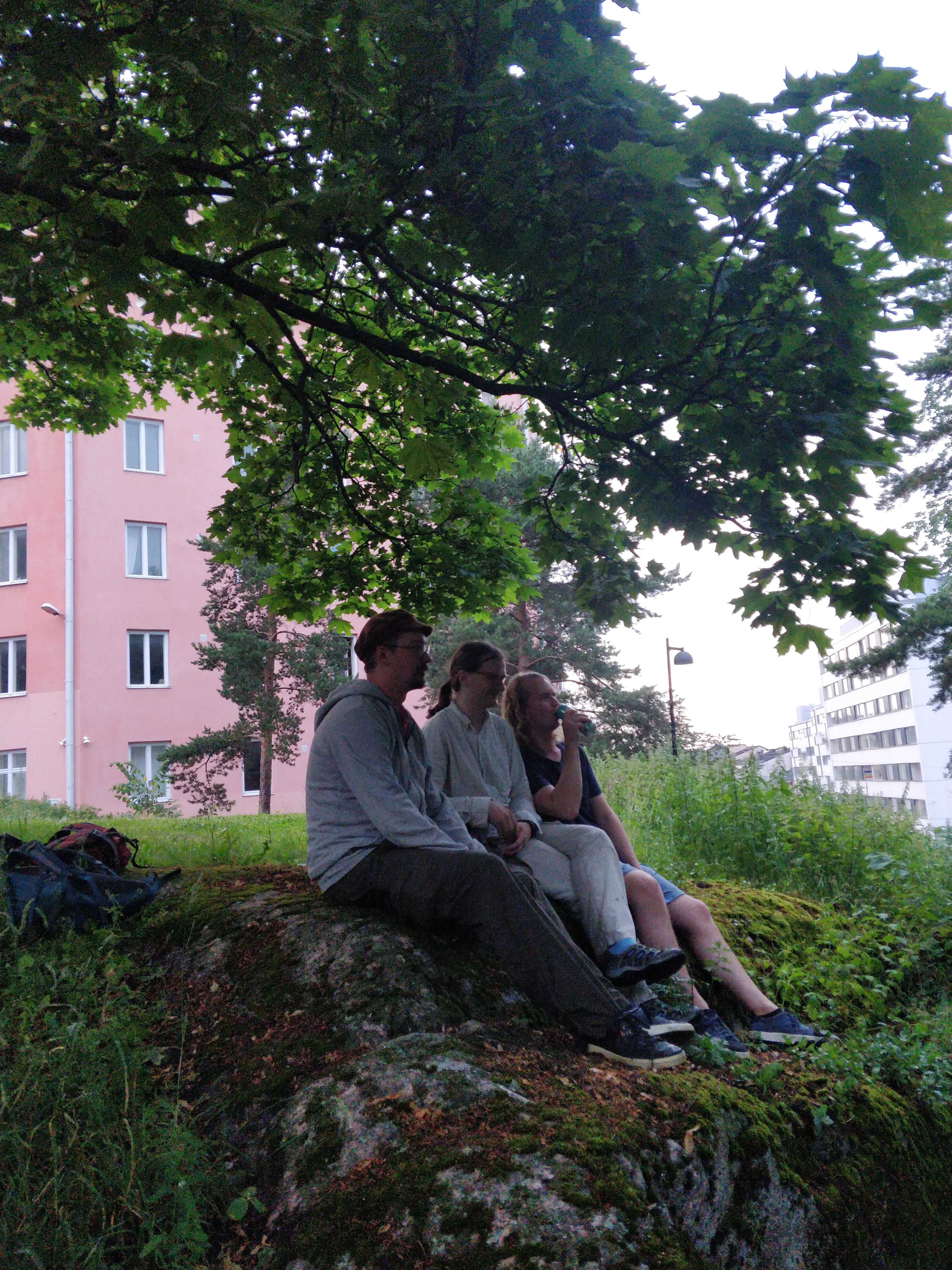 Kolme tyttöä istumassa kallioilla Katri Valan puistossa, takana Vilhonvuorenkuja 20. rephoto