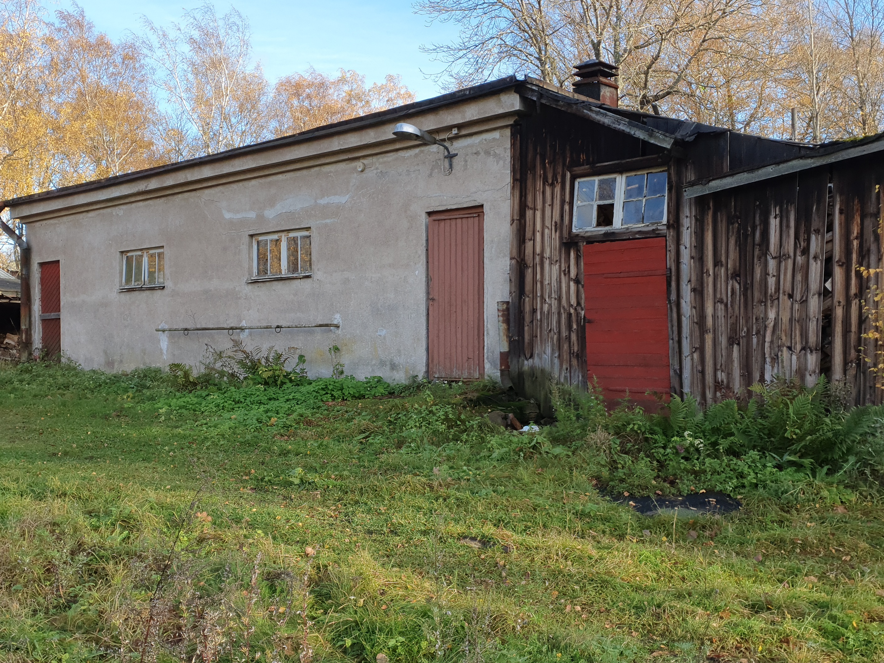 Paloaseman palokalustovaja Vallisaaressa. Siinä säilytettiin aikanaan T-mallista Fordia, kuorma-autoa ja hevosvetoisia kärryjä. Keskimmäisestä ovesta kuljettiin kahden hevosen talliin ja viereisestä punaisesta ovesta hevosten rehu- ja heinävarastoon. Pihapiiriin kuuluu myös vasemmassa reunassa näkyvä puusepänverstas. Valokuva on otettu aurinkoisella säällä. rephoto