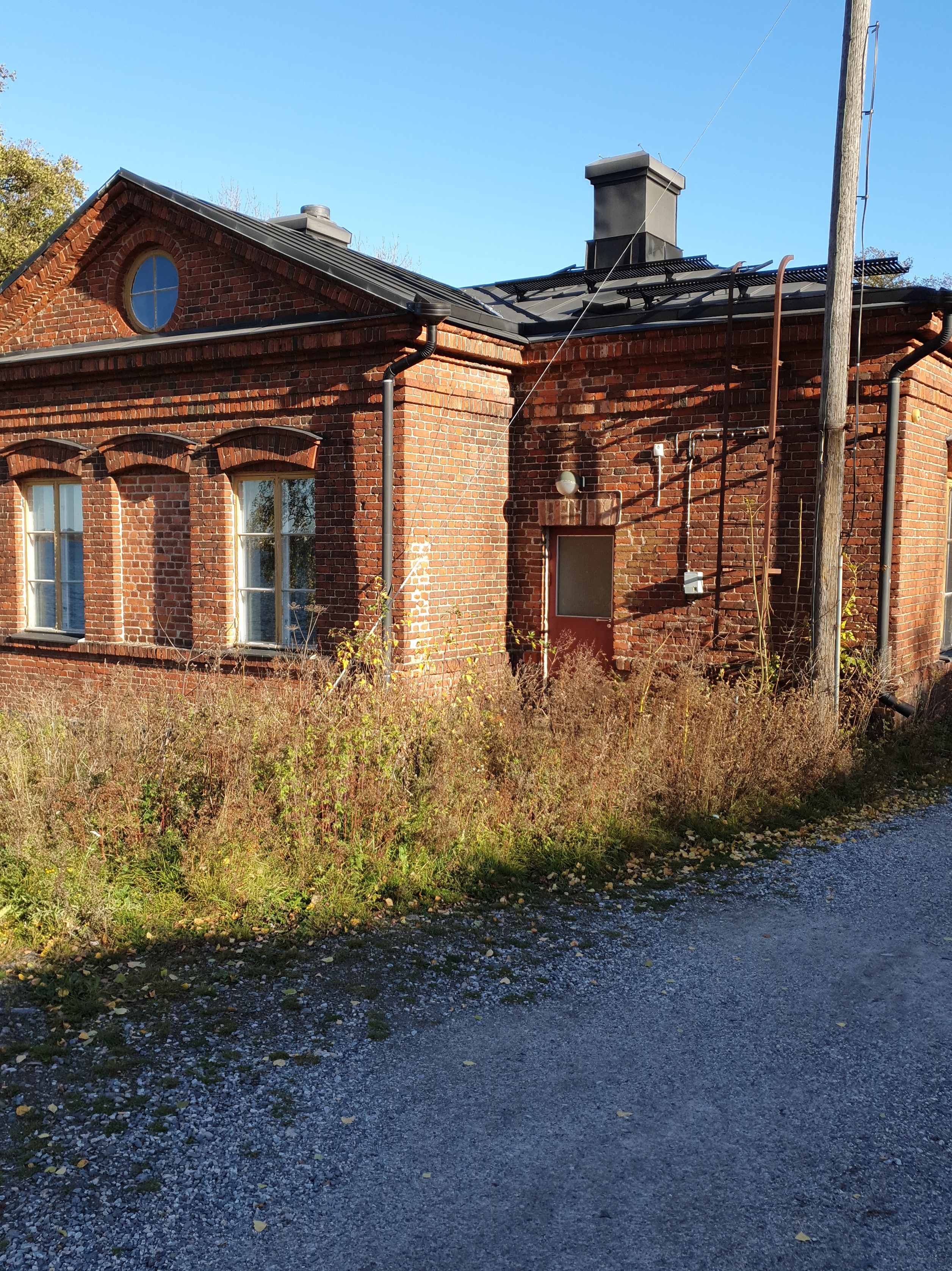 Vallisaarelaisia saaren luotsitalon pihapiirissä. Kaksi miehistä on sotilasunivormussa. Toisella naisista on sylissään pieni lapsi. Taustalla näkyvä tiilirakennus on luotsitalon sauna- ja pyykkitupa. rephoto