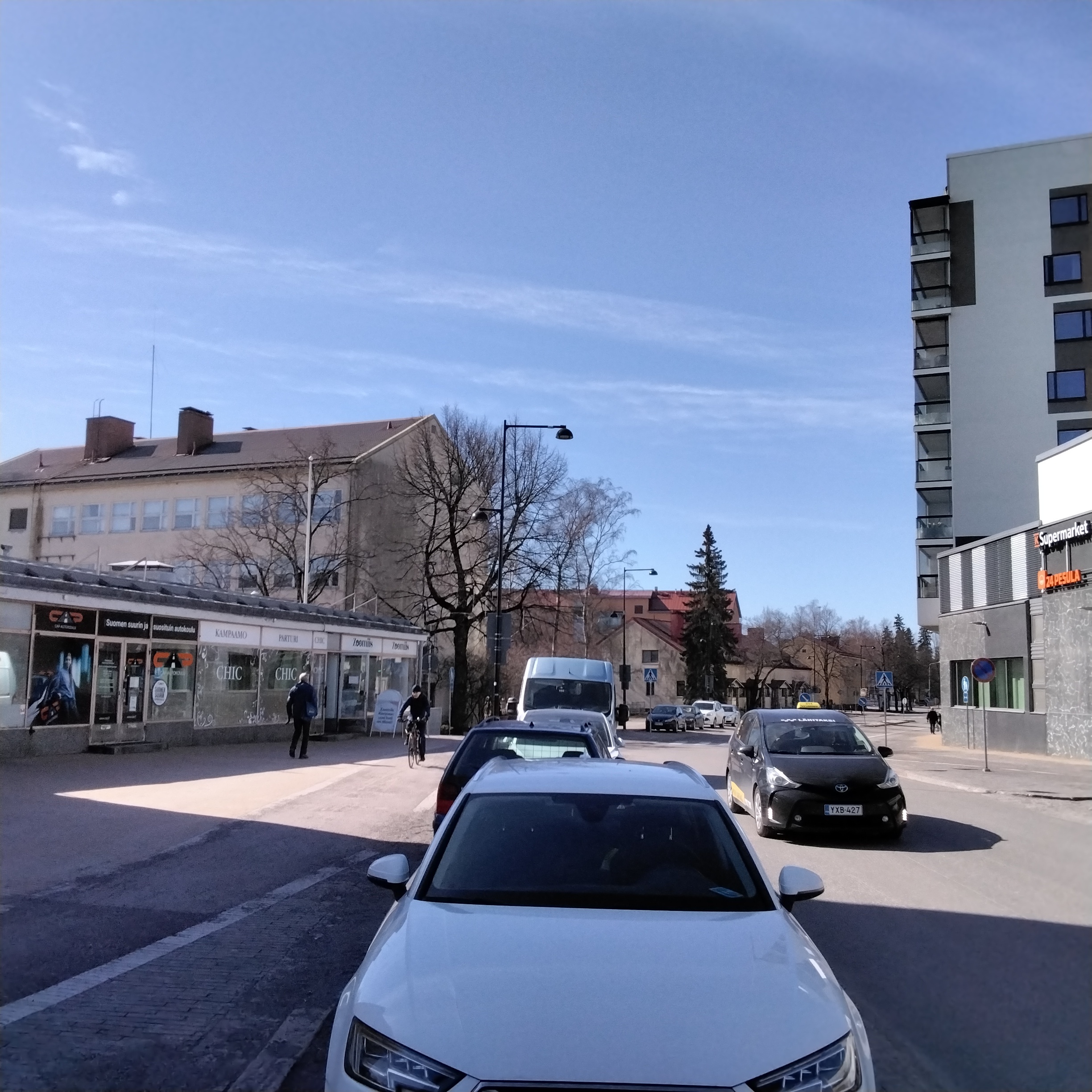 Katunäkymä Aleksis Kiven tien varrelta 1950-luvun jälkipuoliskolta. Vasemmalla vuonna 1957 valmistuneen Suomen Työväen Säästöpankin (STS) matala liikesiipi, jonka takana Keravan kauppalantalo. Kauppalantalon päädyssä Keravan ensimmäinen kuntavaakuna. Kauppalantalon takana näkyy vuonna 1952 valmistuneet kauppalan virkailijoiden lamellitalo (ns. haitaritalo). Tien oikealla puolen maalarimestari Blommin talon kulmaa, jossa kuvaushetkellä toimi Kelloliike T.Soikkeli.  Päällystämättömällä tiellä pyöräilee pariskunta.
https://muistaja.finna.fi/keravan_museopalvelut/Record/kerava_mui.mui-15460 rephoto