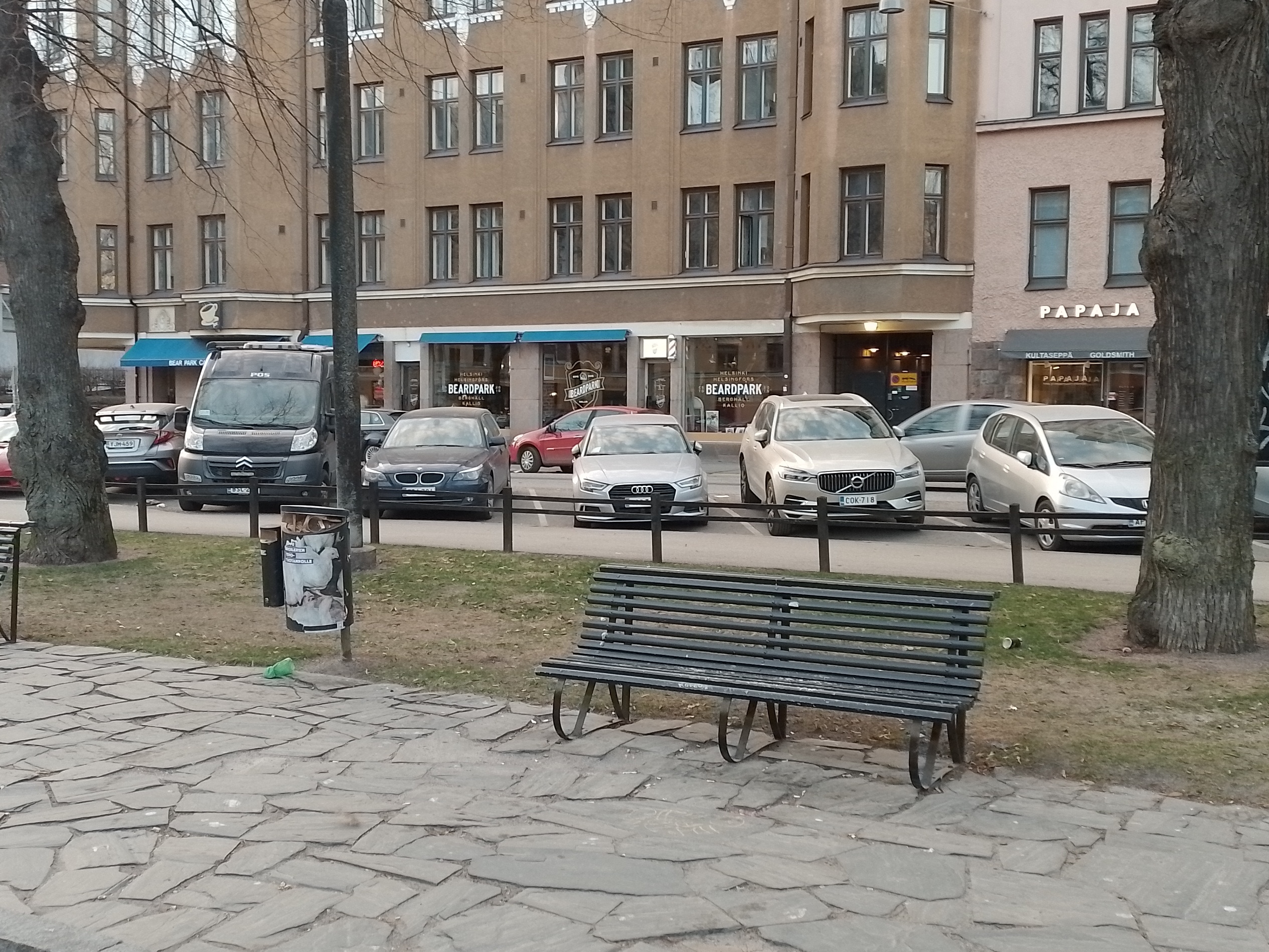 Karhupuisto. Agricolankatu. Mies nuokkumassa penkin päässä ja muita ihmisiä istumassa penkillä Karhupuiston laidalla puistotapahtuman aikaan. rephoto