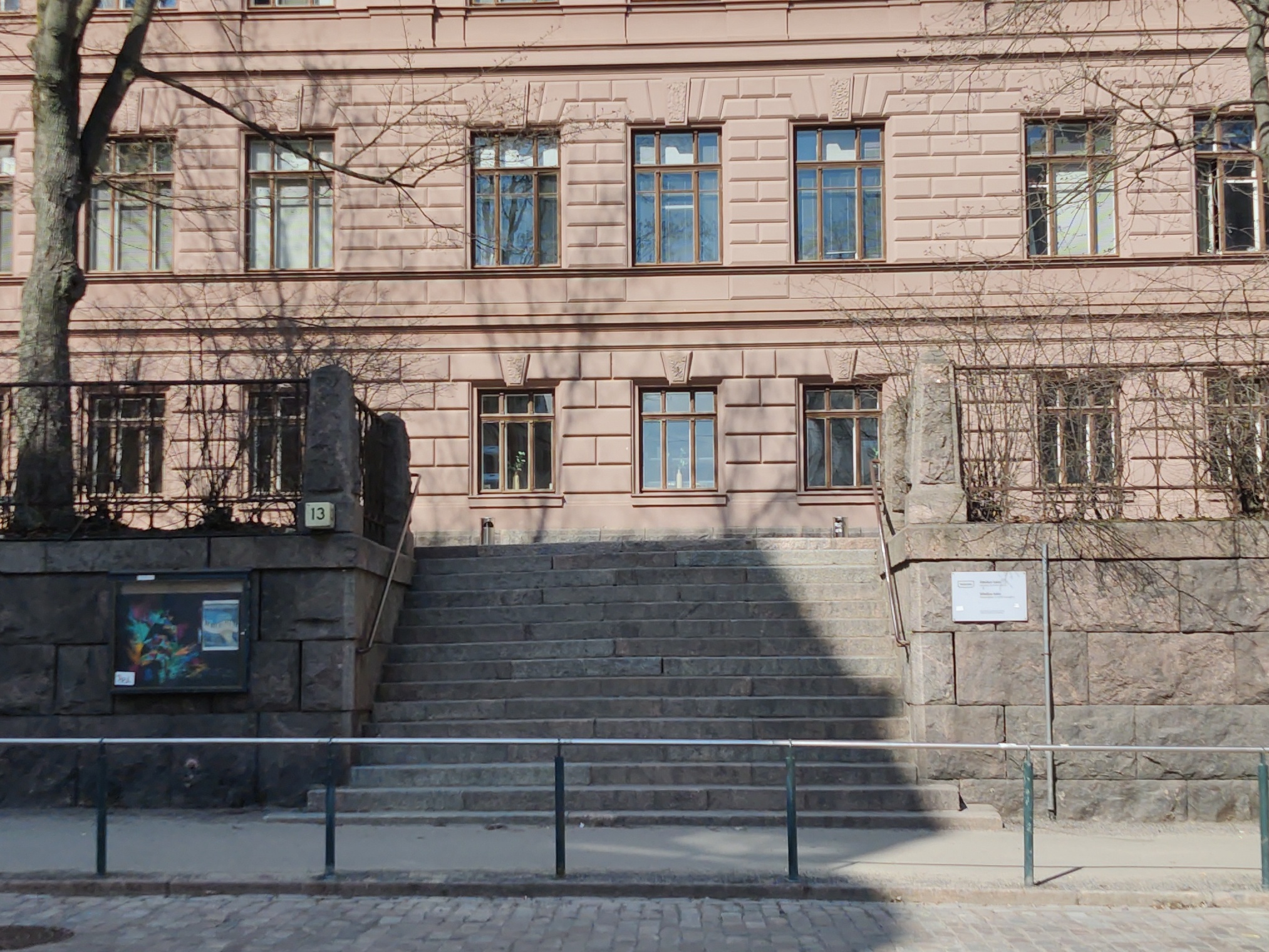 Liisankatu 13. Koulun huurteiset, lumiset portaat penkkariajelupäivänä Liisankatu 13:ssa. Portaiden yläpäässä banderolli, jossa teksti ARBEIT MACHT FREI?!. rephoto