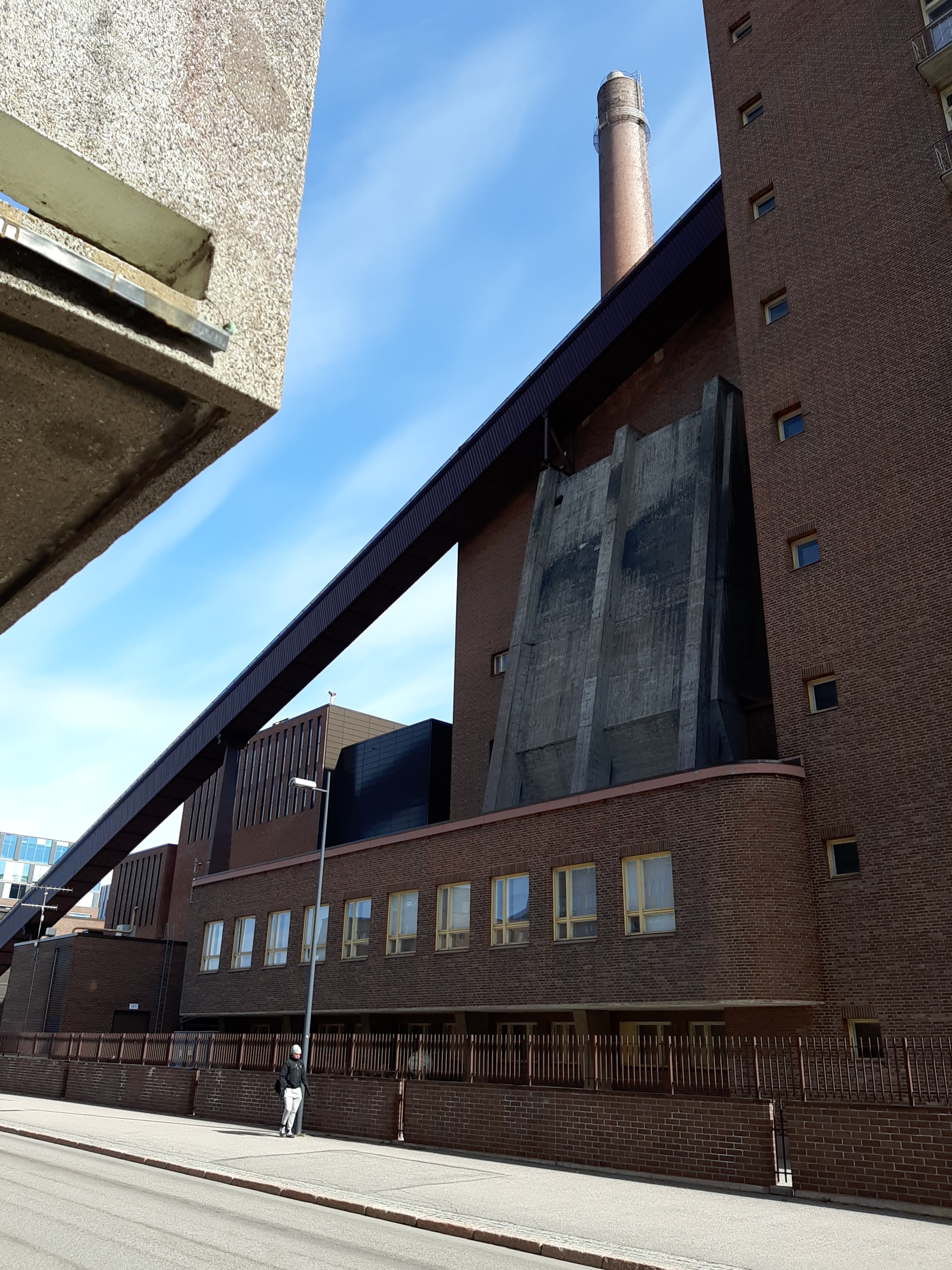 Osa Helsingin sähkölaitoksen Salmisaaren voimalaa, Lauttasaarenkatu 11 (nyk. Porkkalankatu 9-11), nähtynä Tallberginkadun varrelta, Porkkalankadun pohjoispuolelta. Voimalarakennuksen yläkertaan nousee hiiltä voimalan polttoaineeksi kuljettava linjasto. Voimala A otettiin käyttöön vuonna 1953. Valokuvan nurkissa näkyvät kaareutuvat tummat varjot, jotka johtuu siitä, että valokuvaaja on käyttänyt kuvatessaan vastavalosuojaa. rephoto