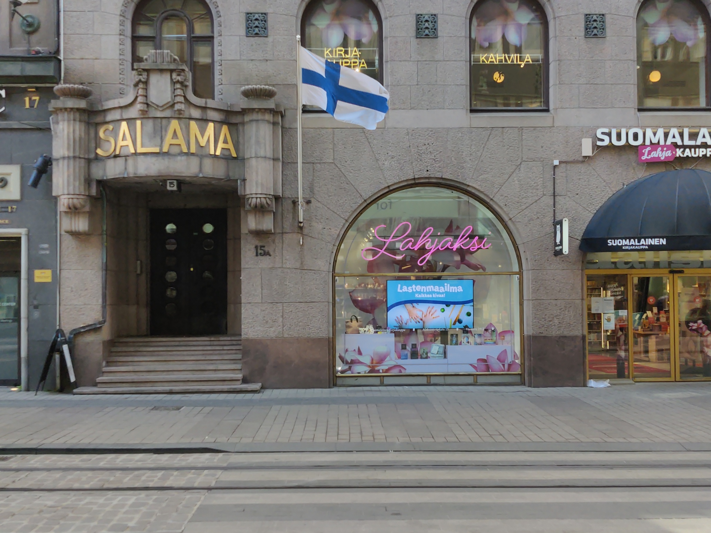 Salaman talo ja 1. kerroksen liikehuoneistoja. Kahdessa alimmassa kerroksessa on segmenttikaari-ikkunat. Julkisivun kummassakin reunassa on sisäänkäynti, ja näiden sivusisäänkäyntien yläpuolella lukee teksti Salama vakuutusyhtiö Salaman mukaan. Lisäksi näiden sisäänkäyntien yläpuolella on pienet parvekkeet. Liikehuoneiston vaatekaupan nimi Asu on kirjoitettu valokirjaimin jokaiseen kolmeen segmenttikaareen. Punainen pakettiauto on parkkeerattu vaatekaupan eteen sointuen vaatekaupan punaisiin valokiurjaimiin ja markiiseihin. Airam Electric Oy Ab:n  kuvamateriaalia. rephoto