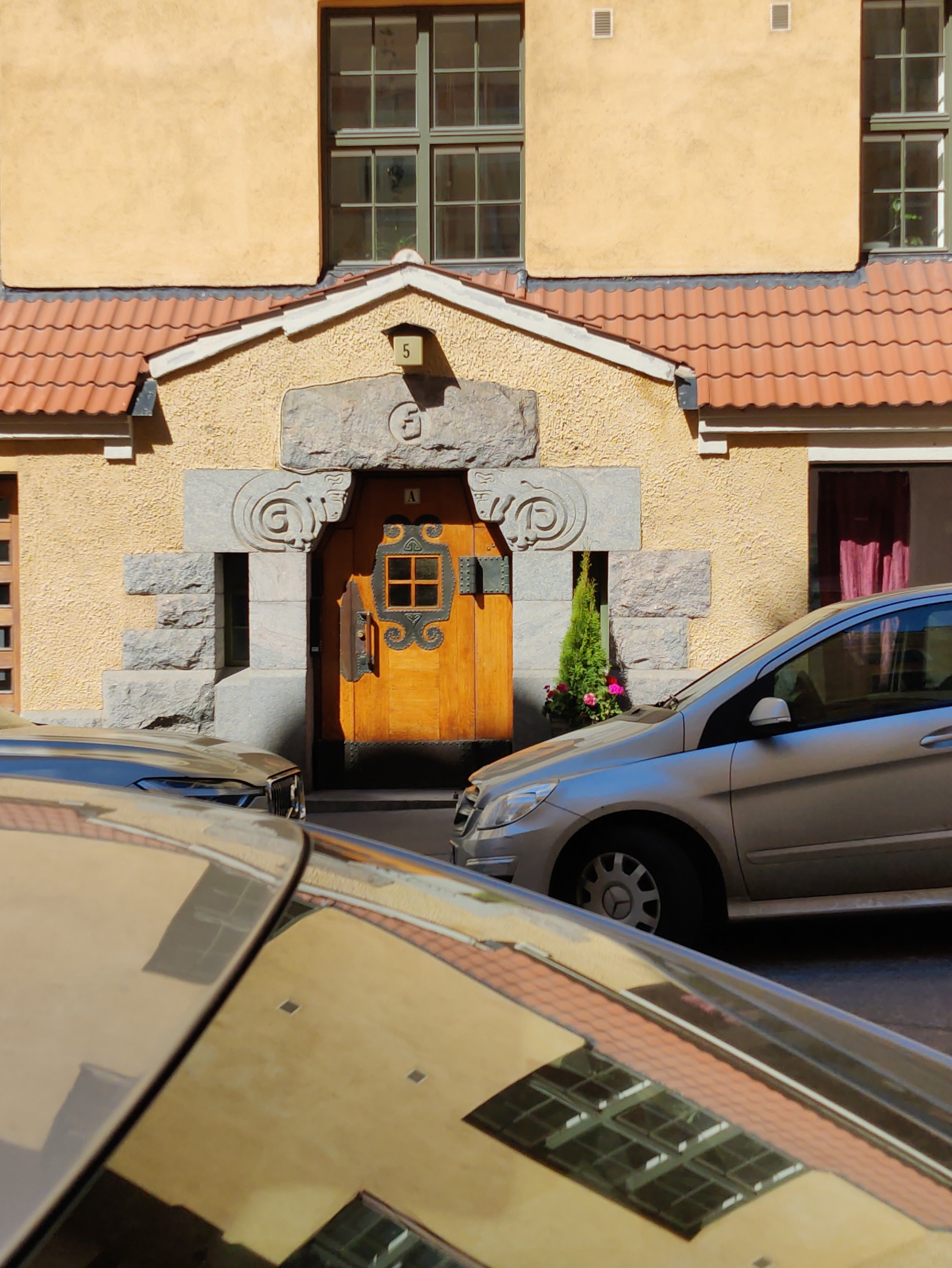 Kiinteistö Oy Eol, Luotsikatu 5 A. Arkkitehtitoimisto Gesellius, Lindgren, Saarinen. Sisäänkäynti. Jykevässä puuovessa koristeellisia takorautadetaljeja (helat, ikkunakehys) sekä värillisestä lasista valmistettu neliruutuinen ikkuna. Luonnonkiviportaali, jossa puskevat pässit. Vuonna 1901 suunniteltu talo on hyvä esimerkki alkuperäisessä asussaan säilyneestä Katajanokan art nouveau -kaupunginosan luonnonkivestä ja tiilestä rakennetusta asuintalosta. rephoto