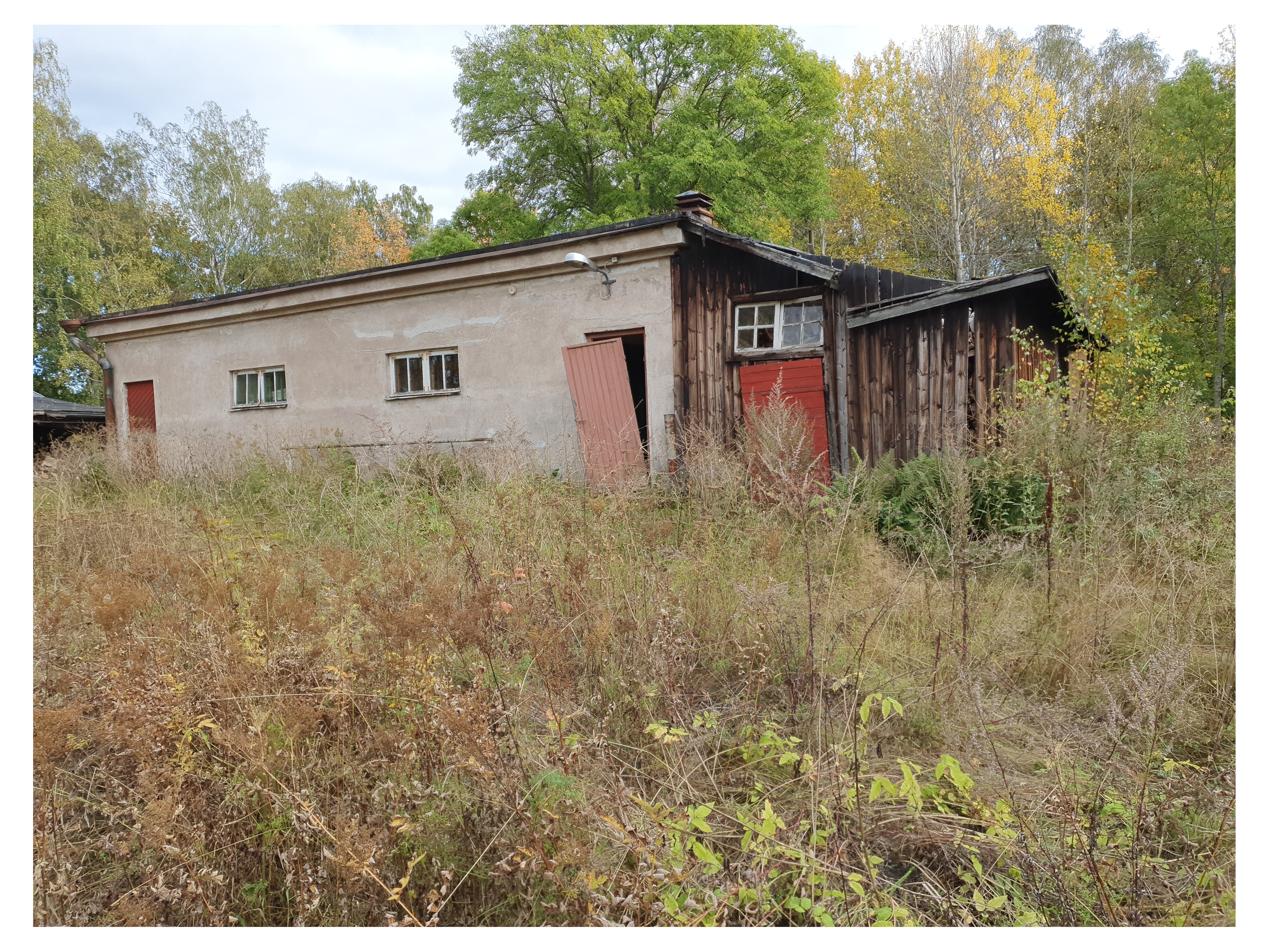 Paloaseman palokalustovaja Vallisaaressa. Siinä säilytettiin aikanaan T-mallista Fordia, kuorma-autoa ja hevosvetoisia kärryjä. Keskimmäisestä ovesta kuljettiin kahden hevosen talliin ja viereisestä punaisesta ovesta hevosten rehu- ja heinävarastoon. Pihapiiriin kuuluu myös vasemmassa reunassa näkyvä puusepänverstas. Valokuva on otettu aurinkoisella säällä. rephoto