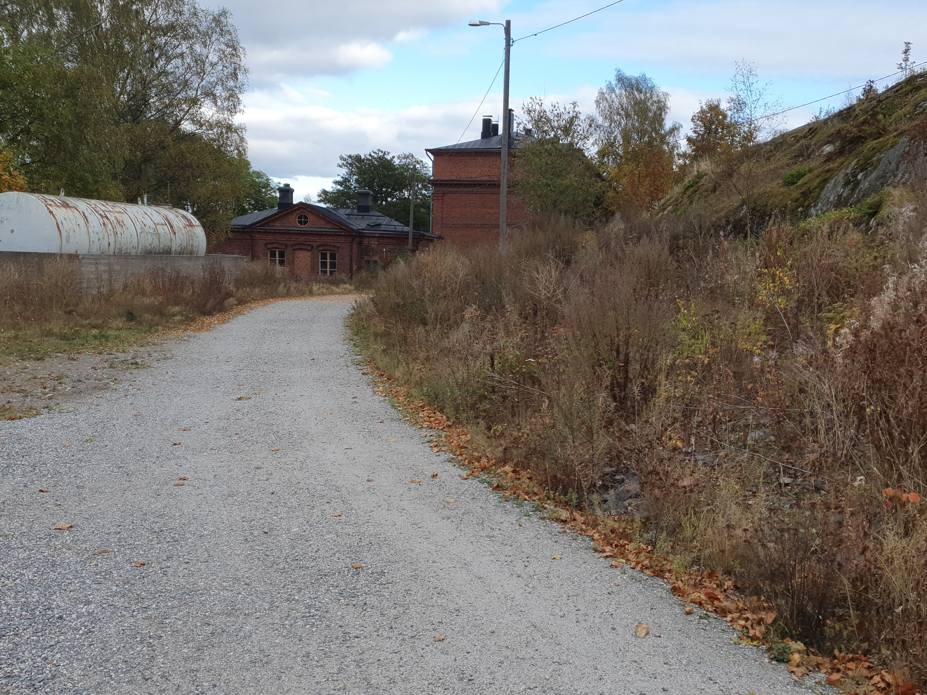 Näkymä Vallisaaresta. Oikealla on luotsitalo ja keskellä näkyy luotsitalon saunan ja pesutuvan rakennus. Vasemmalla alunperin venäläisten varuskuntansa saunaksi rakentama talo. Se on nykyään jo purettu. Tie rakennusten luo on säilynyt. rephoto